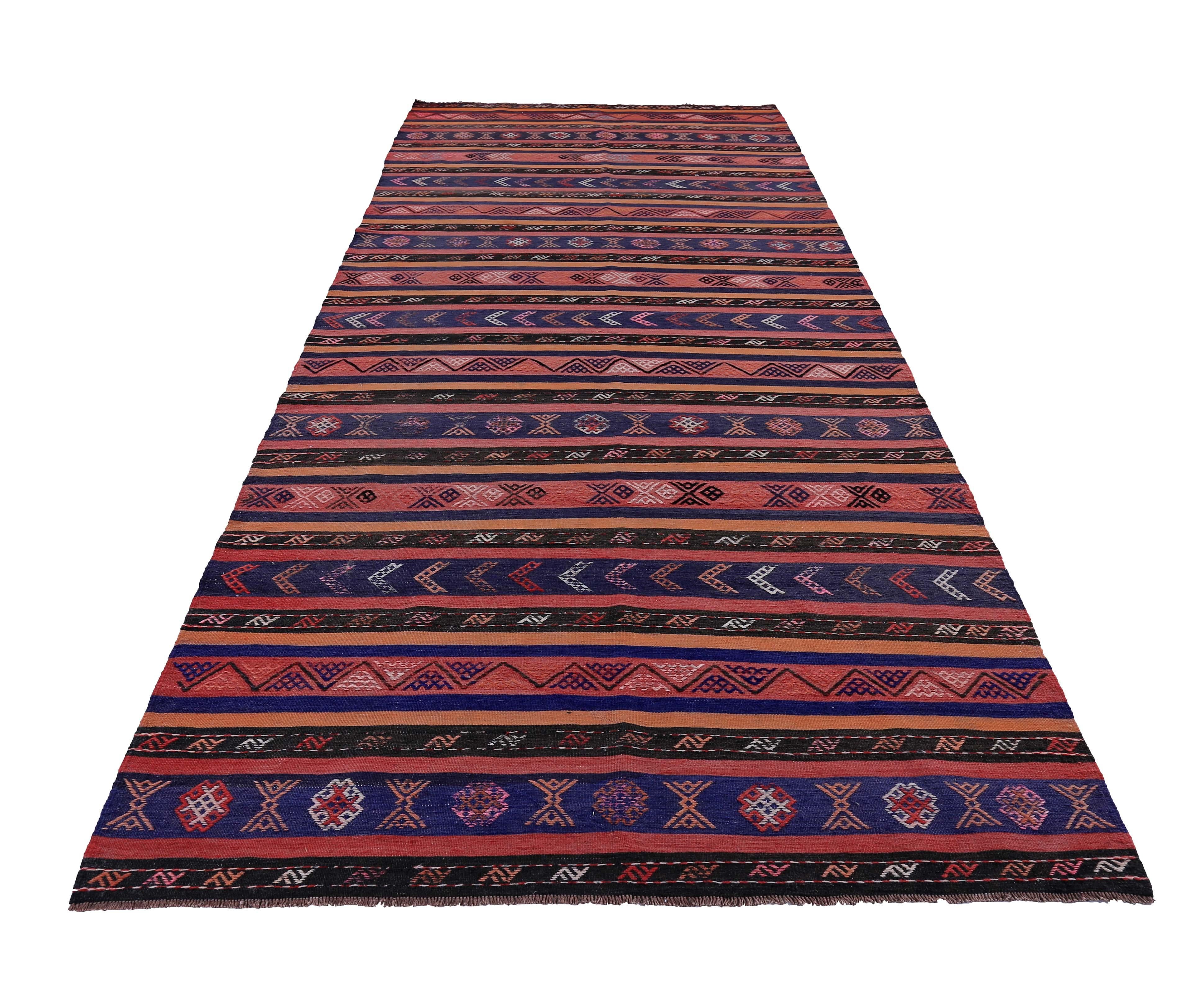 Turkish runner rug handwoven from the finest sheep’s wool and colored with all-natural vegetable dyes that are safe for humans and pets. It’s a traditional Kilim flat-weave design featuring blue, orange and pink tribal stripes. It’s a stunning piece