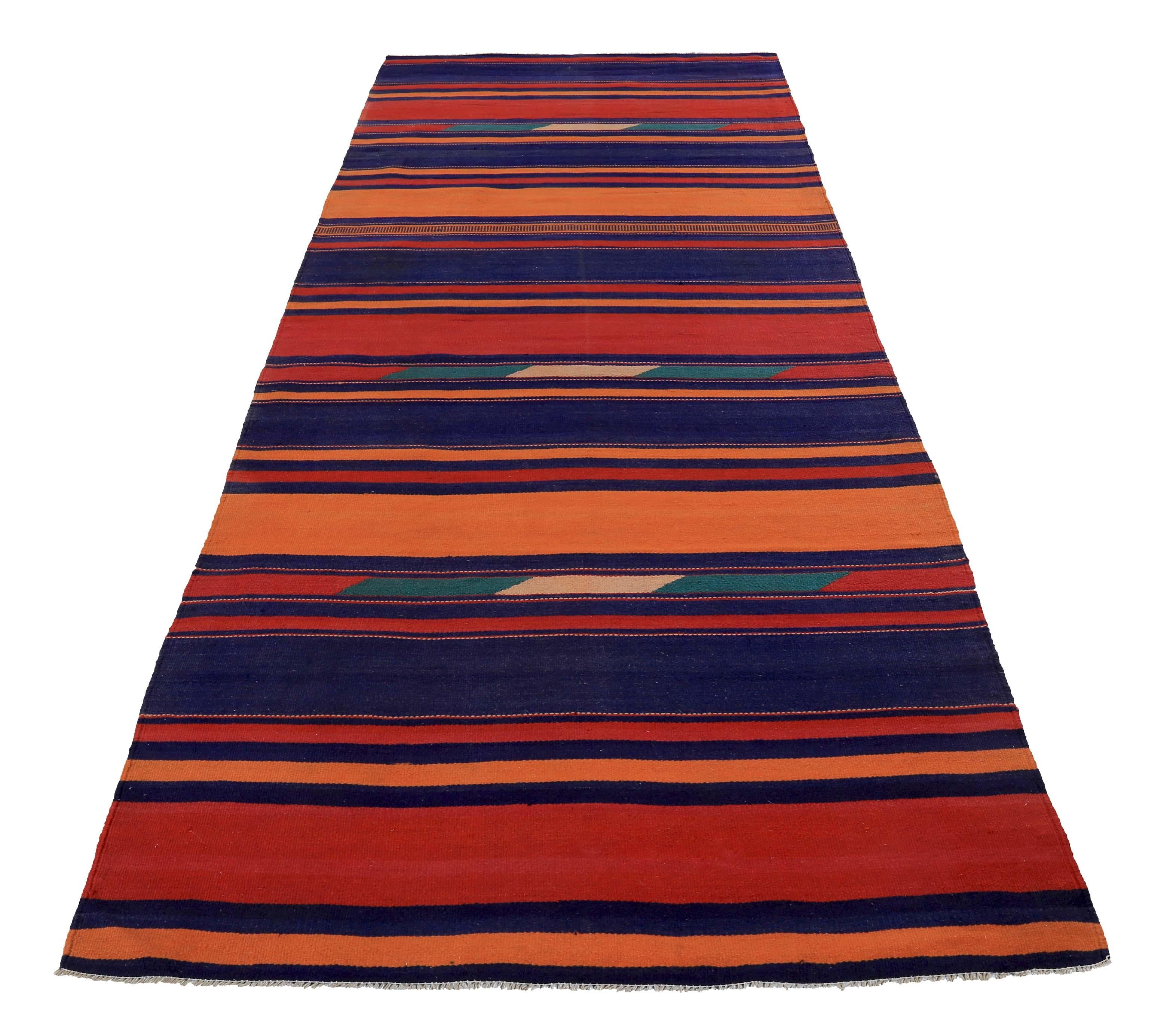 Turkish rug handwoven from the finest sheep’s wool and colored with all-natural vegetable dyes that are safe for humans and pets. It’s a traditional Kilim flat-weave design featuring blue and orange stripes mixed with some green and red hues. It’s a