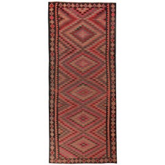 Alfombra turca Kilim con detalles tribales verdes y rosas sobre fondo negro
