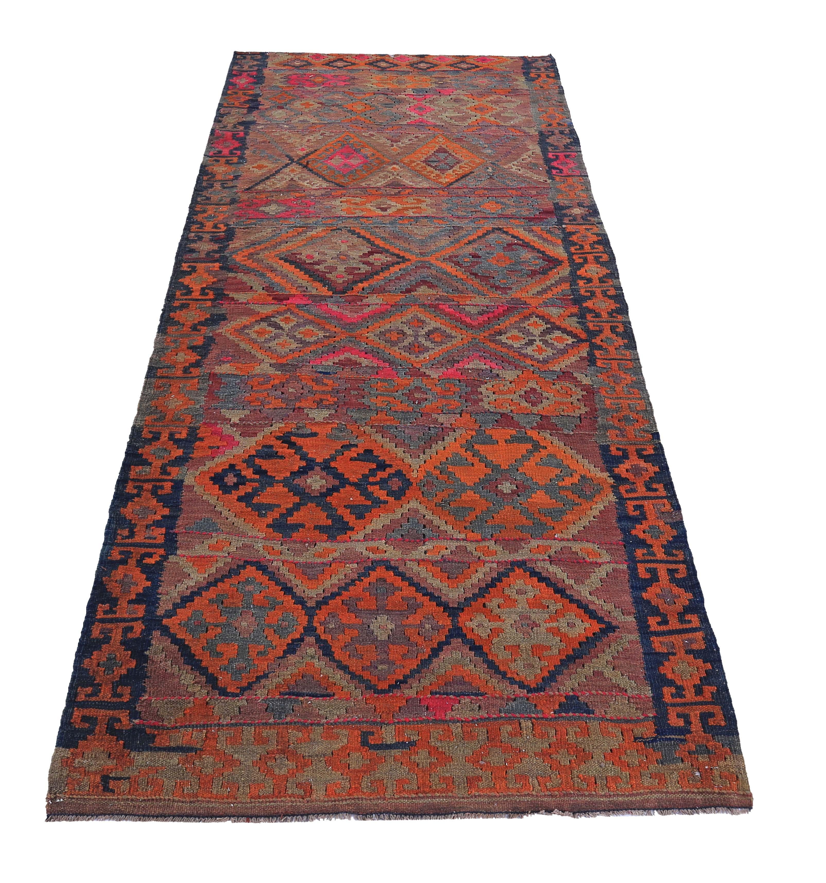 Tappeto turco tessuto a mano con la migliore lana di pecora e colorato con tinture vegetali del tutto naturali e sicure per l'uomo e gli animali domestici. Si tratta di un Kilim tradizionale a trama piatta con motivi a rombi arancioni, blu, rossi e