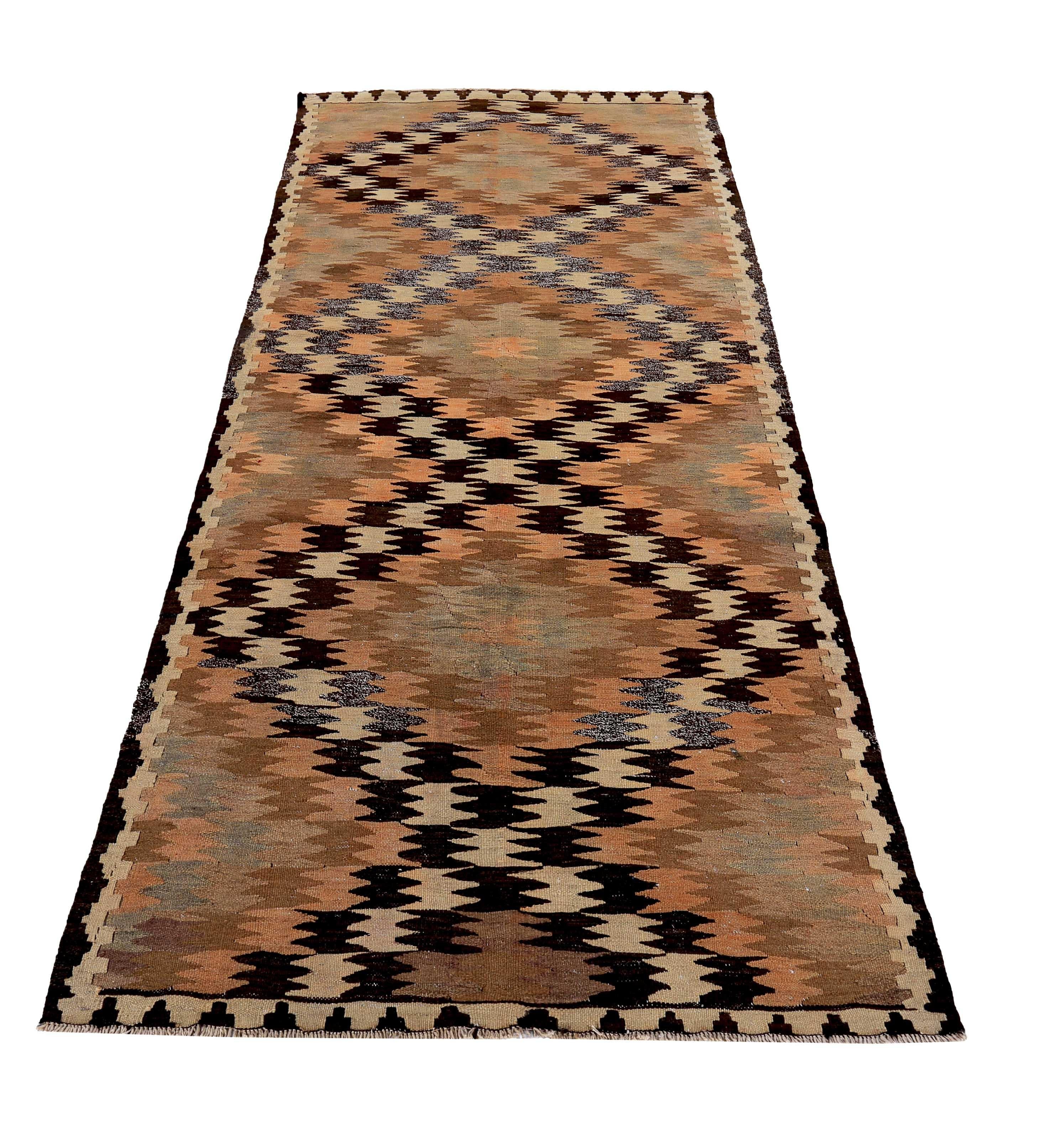 Turkish rug handwoven from the finest sheep’s wool and colored with all-natural vegetable dyes that are safe for humans and pets. It’s a traditional Kilim flat-weave design featuring pink, brown and black tribal diamond patterns on an ivory field.