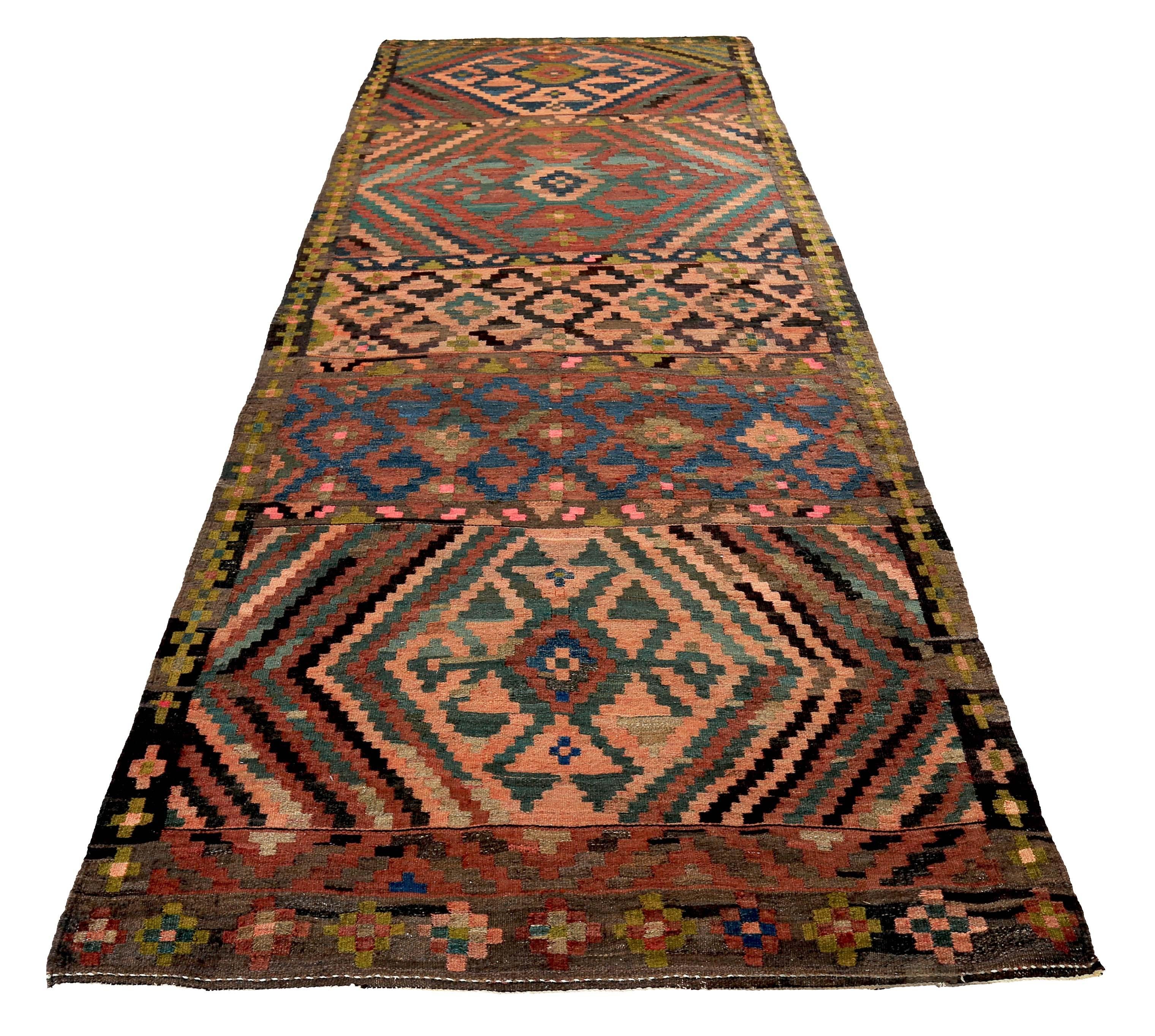 Turkish runner rug handwoven from the finest sheep’s wool and colored with all-natural vegetable dyes that are safe for humans and pets. It’s a traditional Kilim flat-weave design featuring pink and green tribal details over a rich brown field. It’s