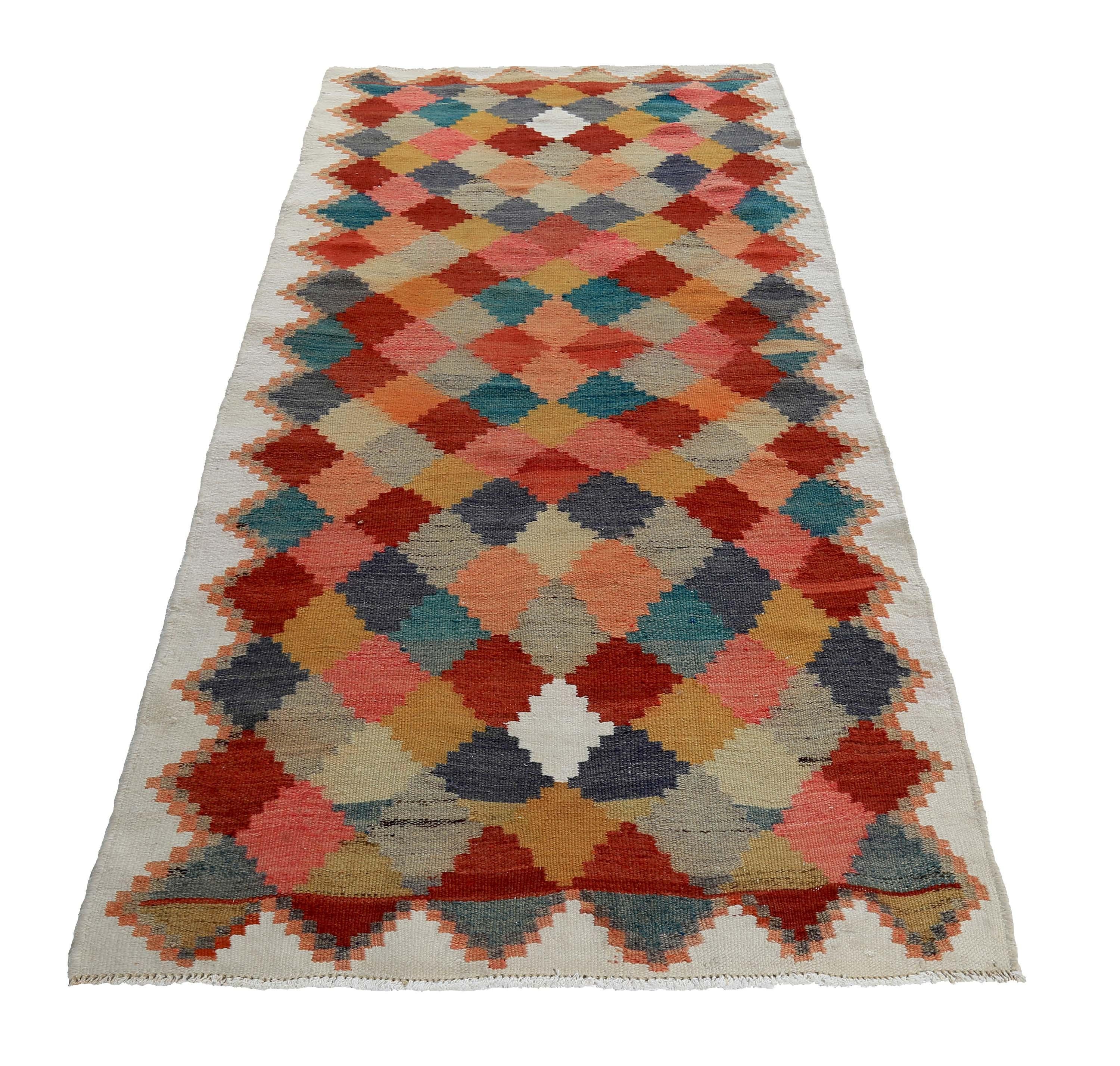 Turkish rug handwoven from the finest sheep’s wool and colored with all-natural vegetable dyes that are safe for humans and pets. It’s a traditional Kilim flat-weave design featuring pink, red and blue tribal diamond patterns on an ivory field. It’s