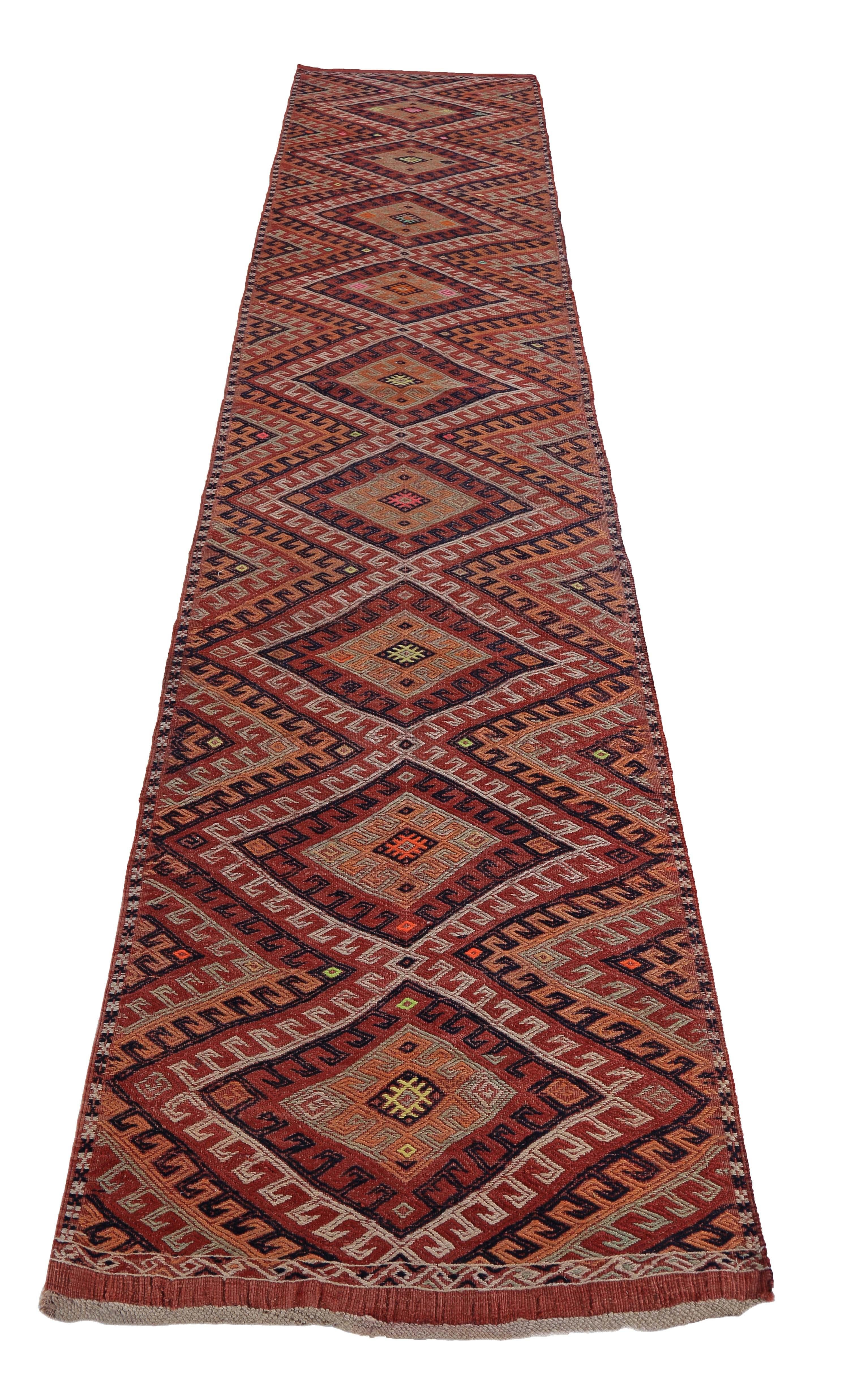 Turkish runner rug handwoven from the finest sheep’s wool and colored with all-natural vegetable dyes that are safe for humans and pets. It’s a traditional Kilim flat-weave design featuring red, orange and ivory tribal patterns. It’s a stunning