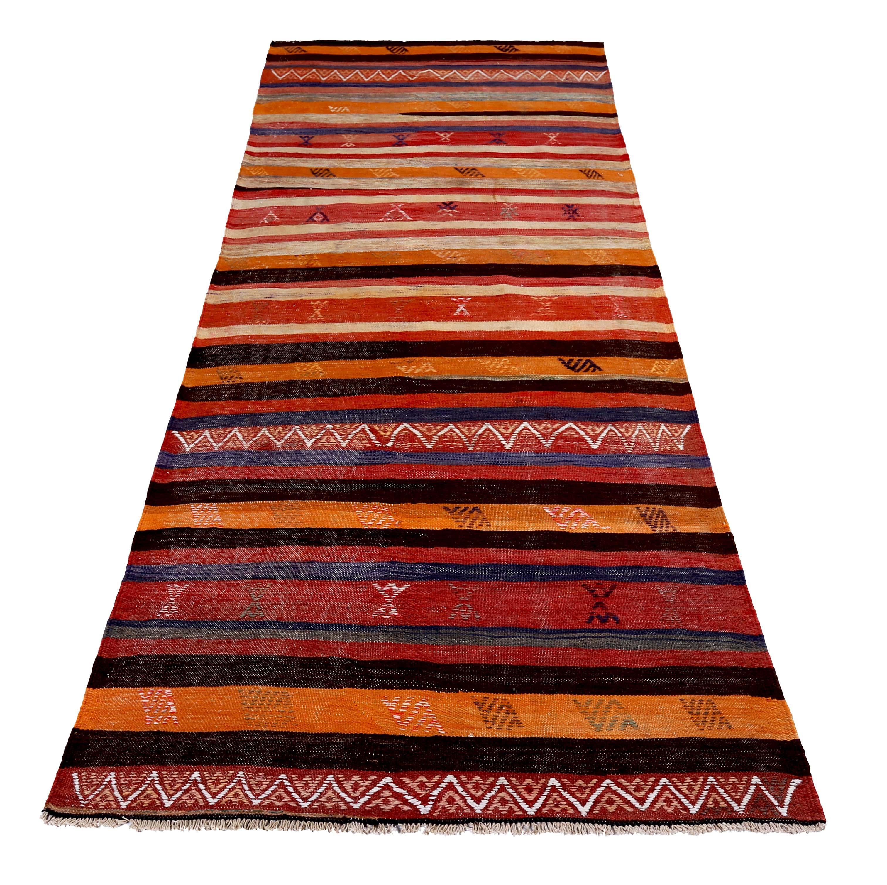 Turkish runner rug handwoven from the finest sheep’s wool and colored with all-natural vegetable dyes that are safe for humans and pets. It’s a traditional Kilim flat-weave design featuring a red and orange stripes with tribal details in white and