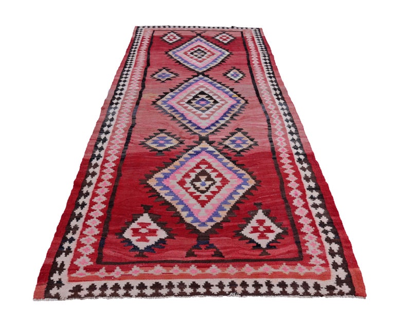 Turkish kilim runner rug handwoven from the finest sheep’s wool and colored with all-natural vegetable dyes that are safe for humans and pets. It’s a traditional Kilim flat-weave design featuring red and pink and white diamond patterns. It’s a