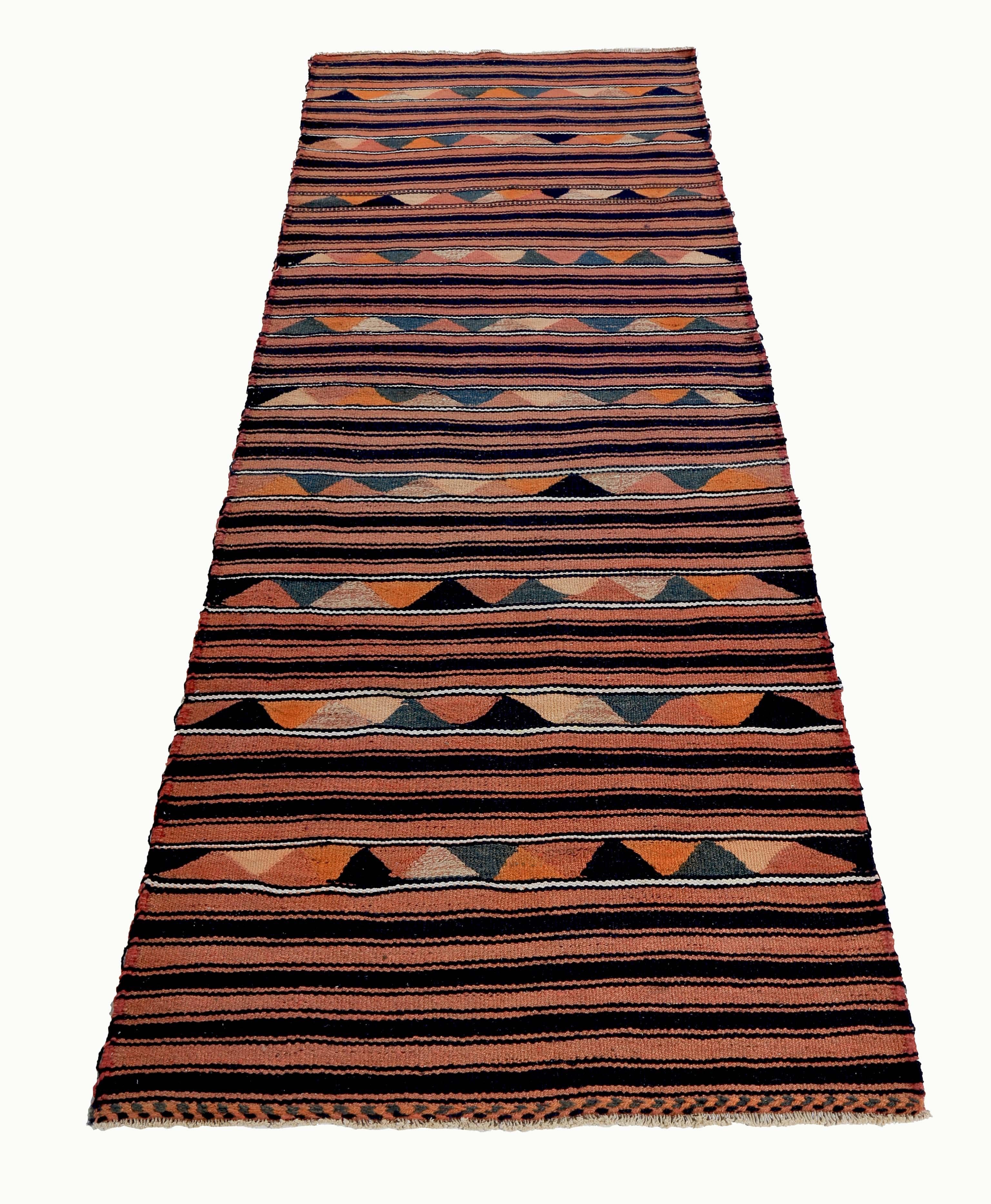 Turkish runner rug handwoven from the finest sheep’s wool and colored with all-natural vegetable dyes that are safe for humans and pets. It’s a traditional Kilim flat-weave design featuring red, black, and orange tribal details. It’s a stunning
