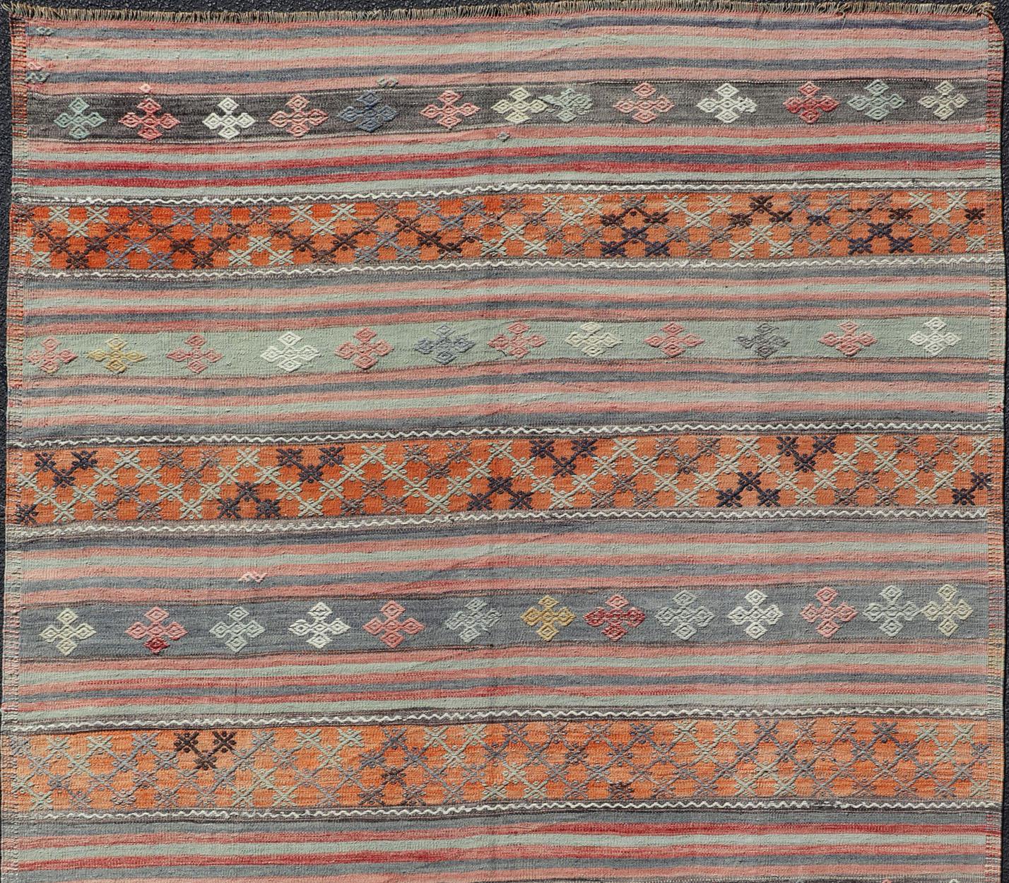 Türkischer Kilim Vintage-Teppich mit verschiedenen Streifenmustern in unterschiedlichen Farben, Teppich TU-NED-1033, Herkunftsland / Art: Türkei / Kelim, ca. Mitte des 20. Jahrhunderts

Dieser einzigartige Mid-Century-Kilim mit einem sich