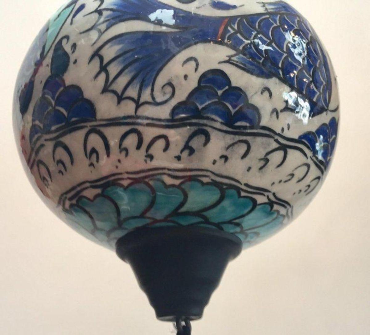 Kütahya pottery hanging ornaments in a bulbous form decorated with fishes underglaze in cobalt blue, turquoise and red on white background.
Cobalt blue silk tassel, hang from a black painted chain.
A Kütahya pottery hanging ornament in polychrome