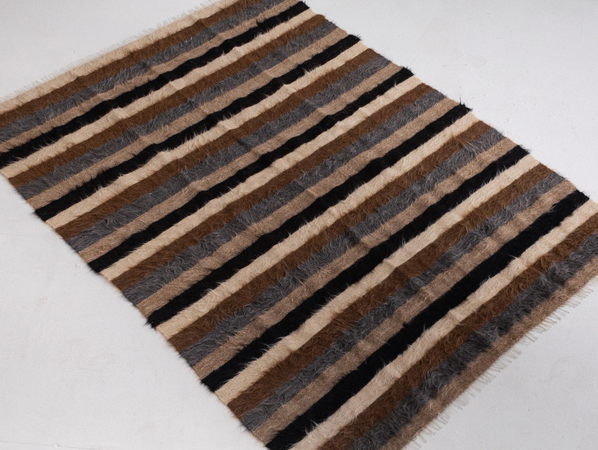 A hand woven Turkish “Siirt” throw. Made with without dyes from natural color mohair goat wool. A thin flat weave with long shaggy fibers give this weaving its unique fuzzy appearance. Thin enough to be used as a throw but thick enough to be used