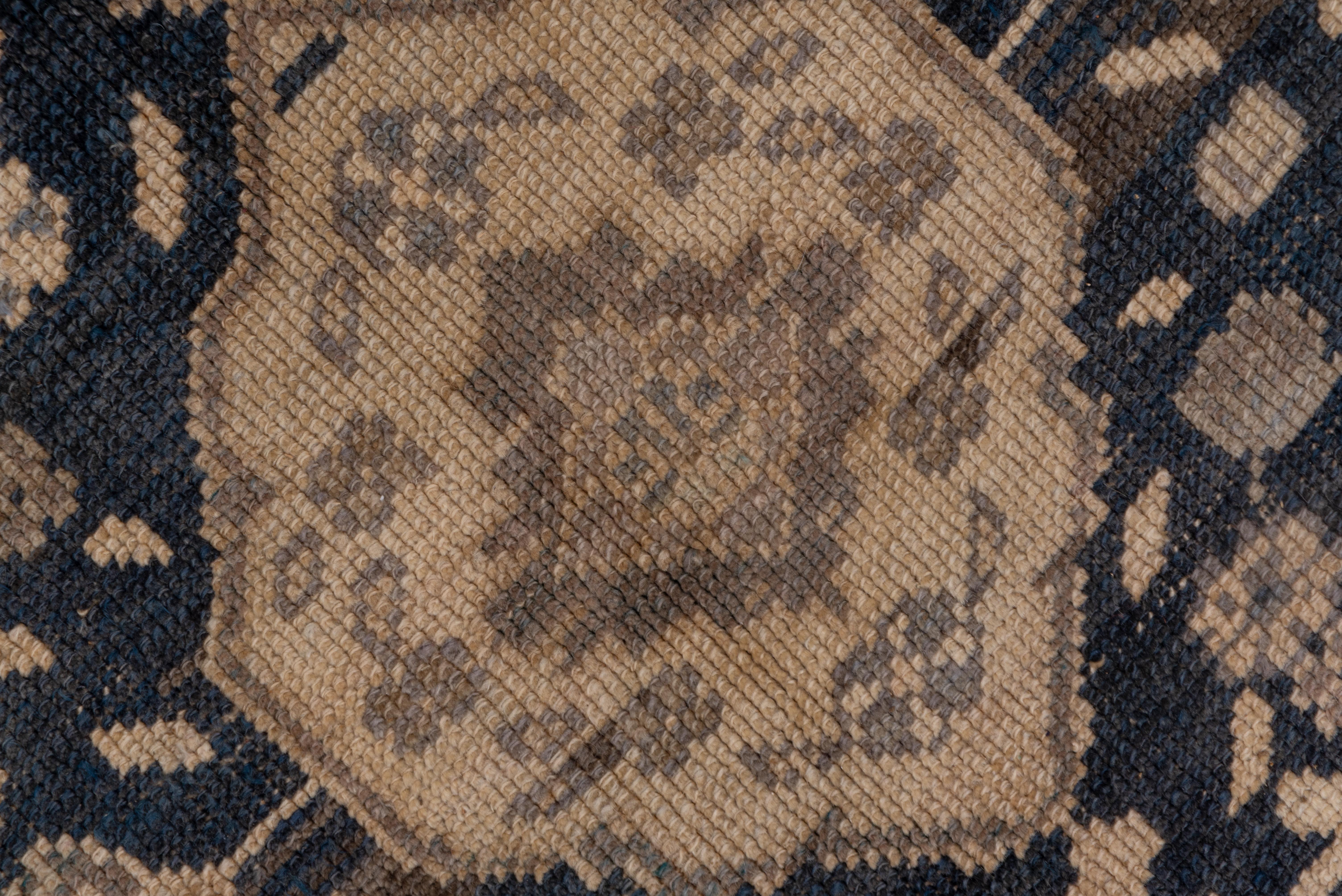 The oatmeal field on this carpet is decorated by five, lobed, slate medallions with hexagonal sand centers and flower in-fills. The slate border features octogrammes, shield palmettes and stylized leaves and floating small rosettes.