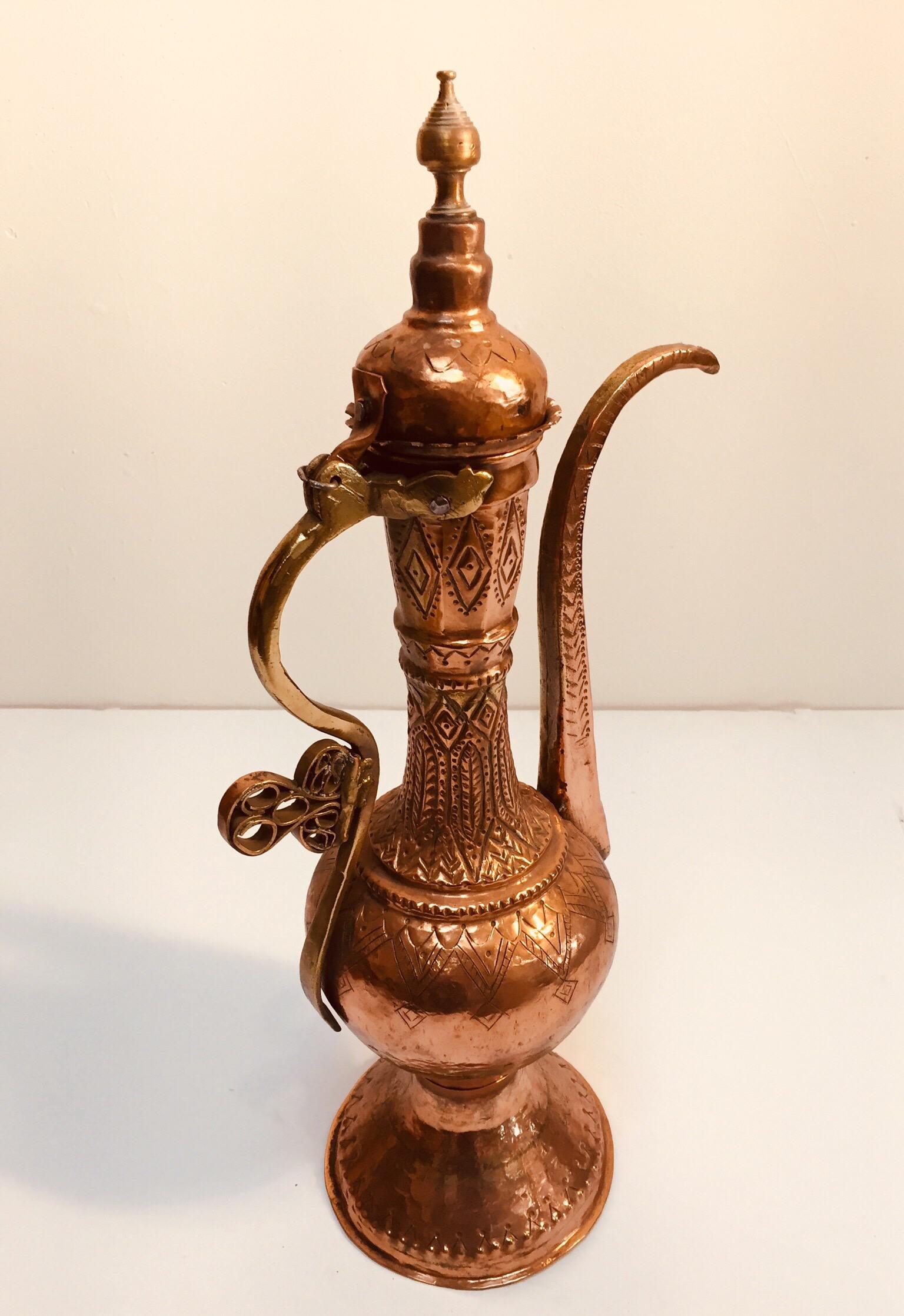 This handcrafted large scale antique 19th century copper Middle Eastern beautiful ewer is a delightful product of the ottoman Empire, with a striking design aesthetic.
The large scale copper metal pitcher with a rounded body, on short splayed foot
