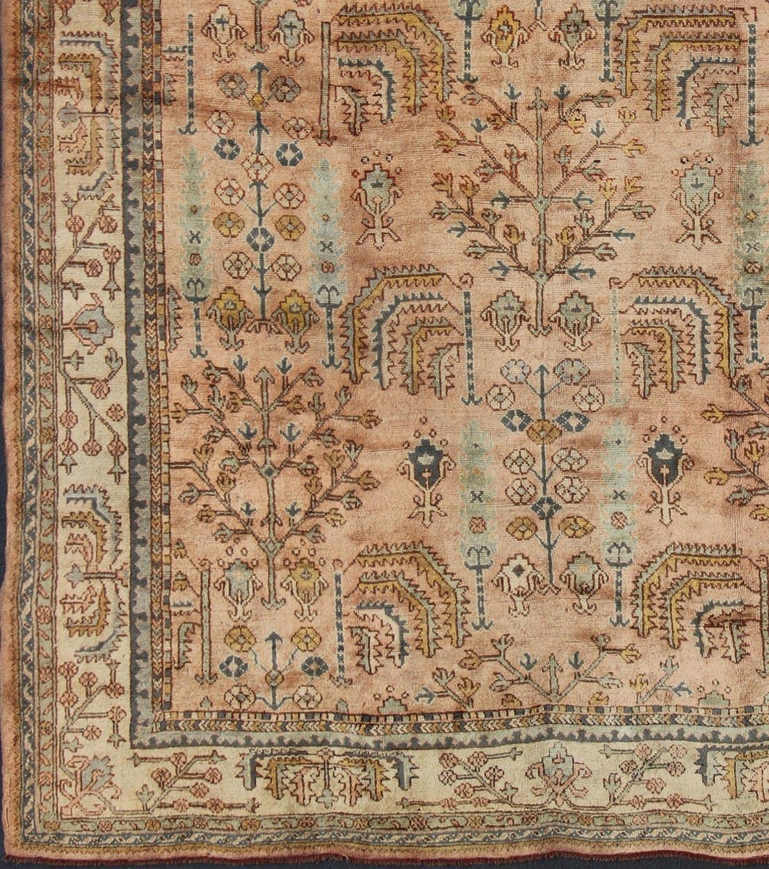 Produced in early 20th century Turkey, this antique Oushak is characterized by a comely and highly representative Oushak composition. Building on traditional designs, this marvelous Turkish rug features an all-over floral design with colors such as