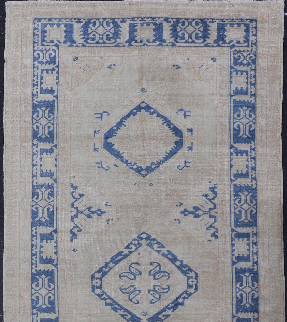 Measures: 5'0 x 13'0 

This beautiful vintage Oushak was hand-knotted in Turkey during the 1940's. The border features stylized motifs, complimentary to the detailing within the central medallions. The field is rendered in a rich blue medallions