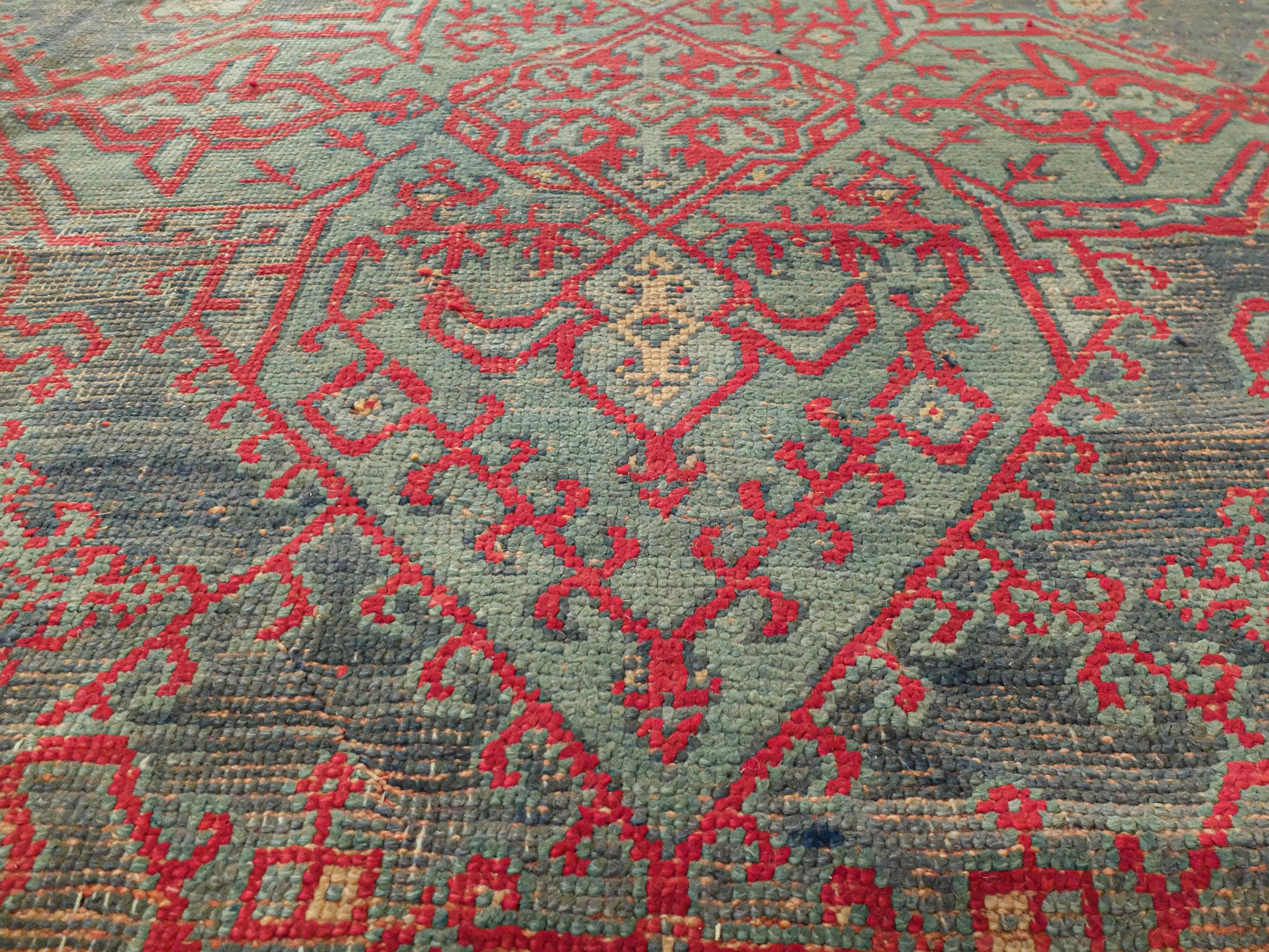 This is a Turkish Oushak rug made c. 1880s. The rug is square measured at 11'6 x 11'6. In its center it has a large diamond shape with intricate patterned detail both inside and wrapped around the outside. Surrounding this shape are four corner