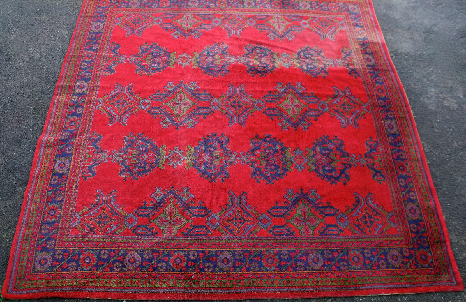 A Turkish Oushak carpet with red ground with repeating indigo guls contained with a foliate border. Measures: 332 x 314 cm.
  