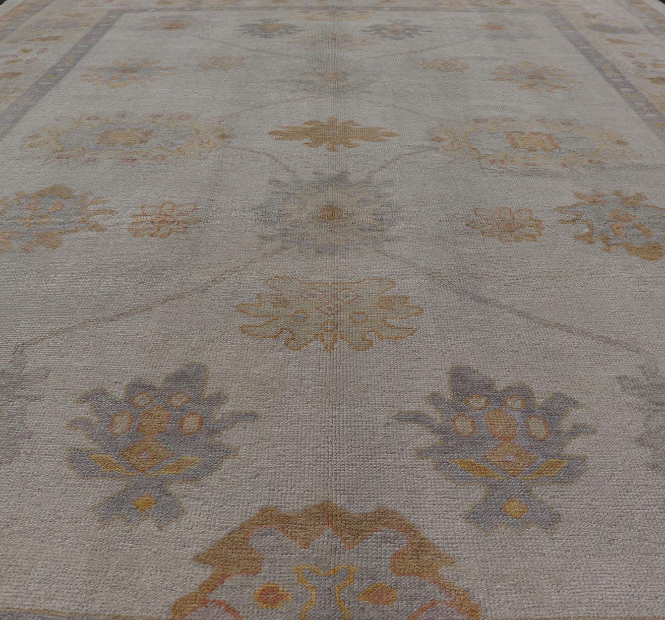 Measures: 10'6 x 14'0 

Turkish Oushak Rug in Gray with Faded Gold, Taupe, and Dusty Blue  10'6 x 14'0.  Keivan Woven Arts. rug /EN-5054 / Early 21st Century, Turkish Oushak.

This hand-knotted Turkish Oushak rug features a graceful palette of soft