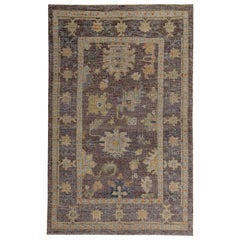 Tappeto turco Oushak con teste di fiori arancioni, verdi e blu su campo marrone