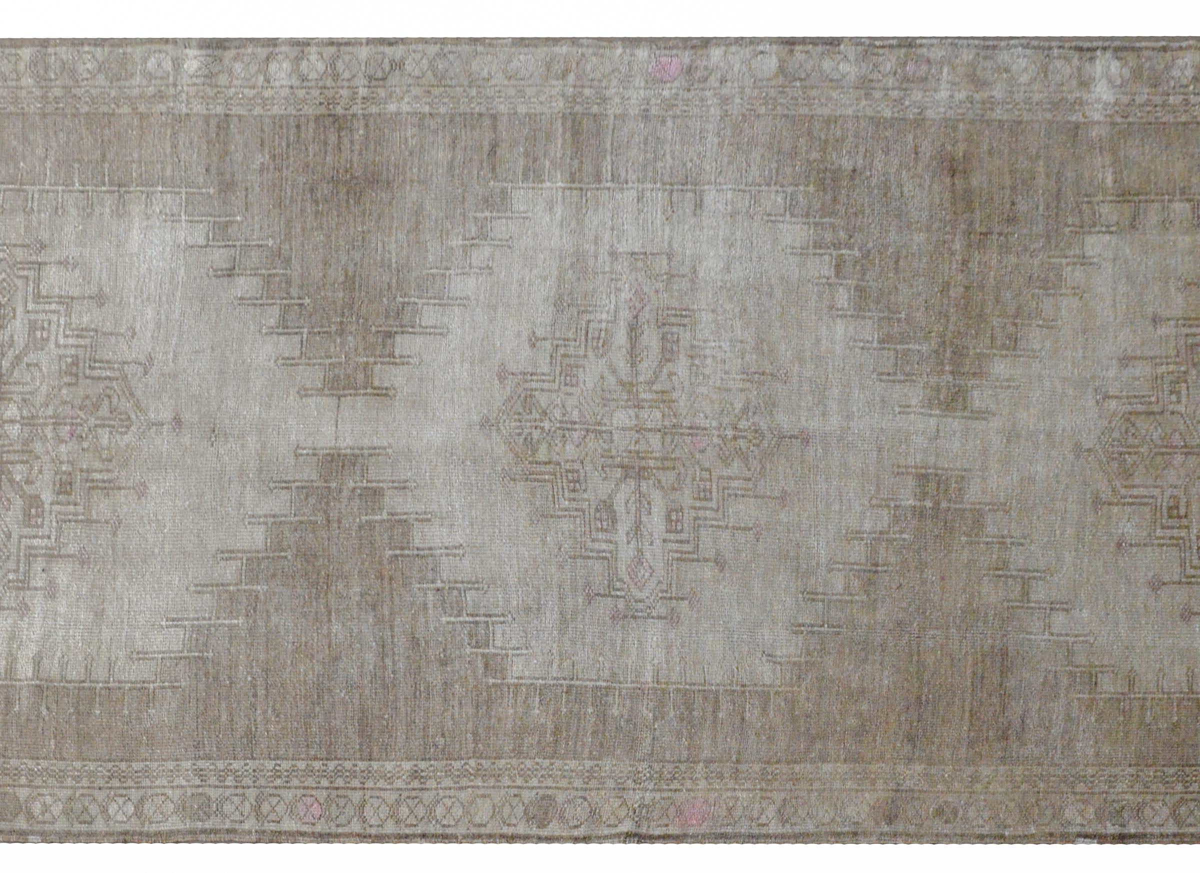 A wonderful vintage hand knotted Turkish Oushak runner with three large medallions woven with stylized floral and vine patterns against a solid cream field, and surrounded by a pattern of stylized flowers. This rug has been given an antiqued wash to