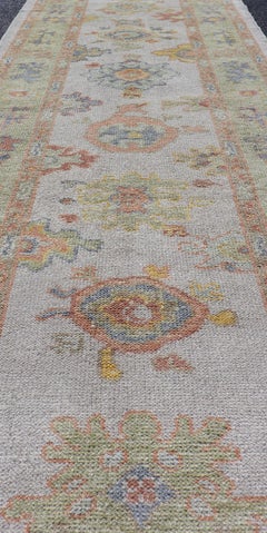 Alfombra turca de Usak en color marfil con tonos verde suave, dorado y coral, de 2'11 x 13'3