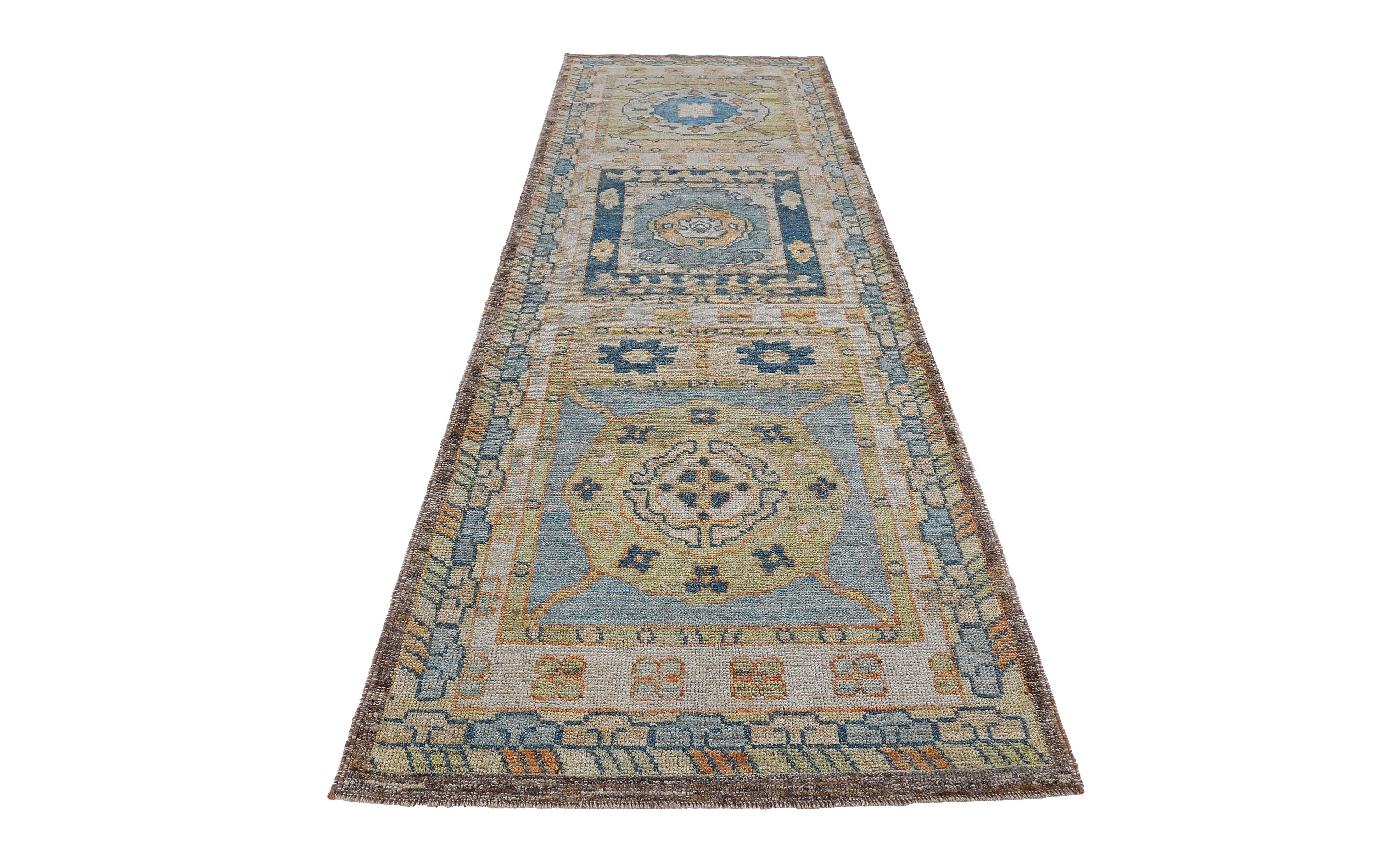Turkish runner rug made of handwoven sheep’s wool of the finest quality. It’s colored with organic vegetable dyes that are certified safe for humans and pets alike. It features blue and orange floral patterns on a beautiful beige and brown field.