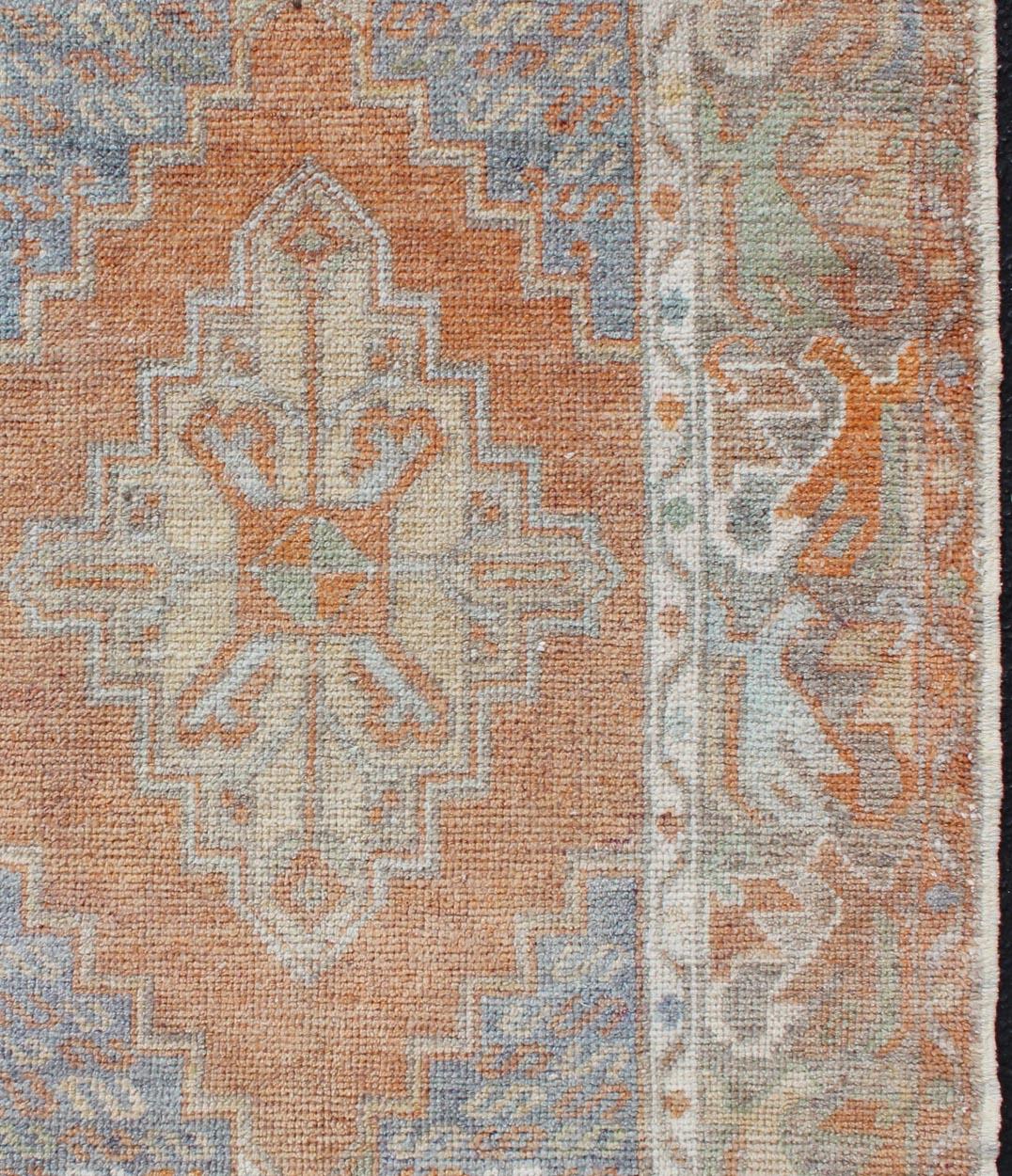 Vintage Oushak small carpet from Turkey in light orange and light Blue & L.Green, rug EN-179663, country of origin / type: Turkey / Oushak, circa 1950

This vintage Turkish oushak rug features an intricately designed medallion resting in the