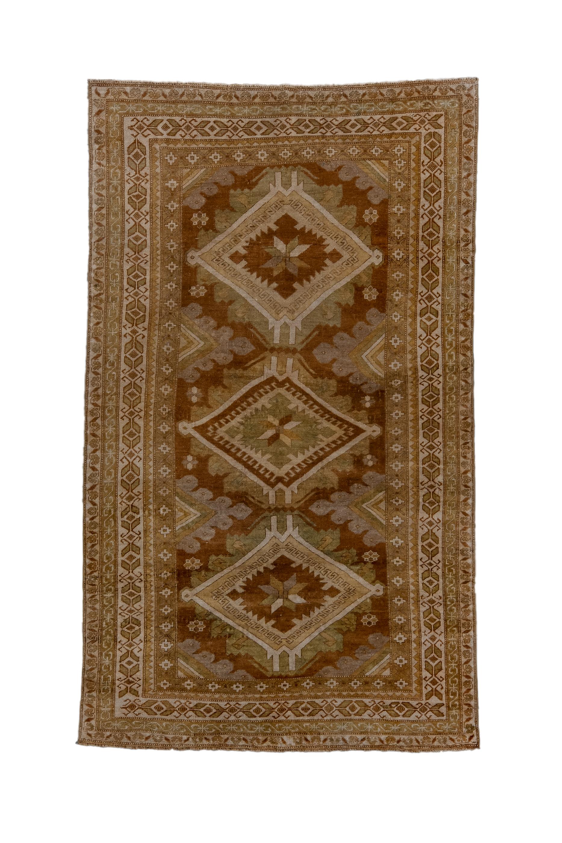 The Turkey red field displays three lozenge-shaped floating medallions, with lobate edges and star-in-ashik centres. Half, triangular elements, with lobed edges, project in from the sides. Green, straw and teal accents. Ecru major border with