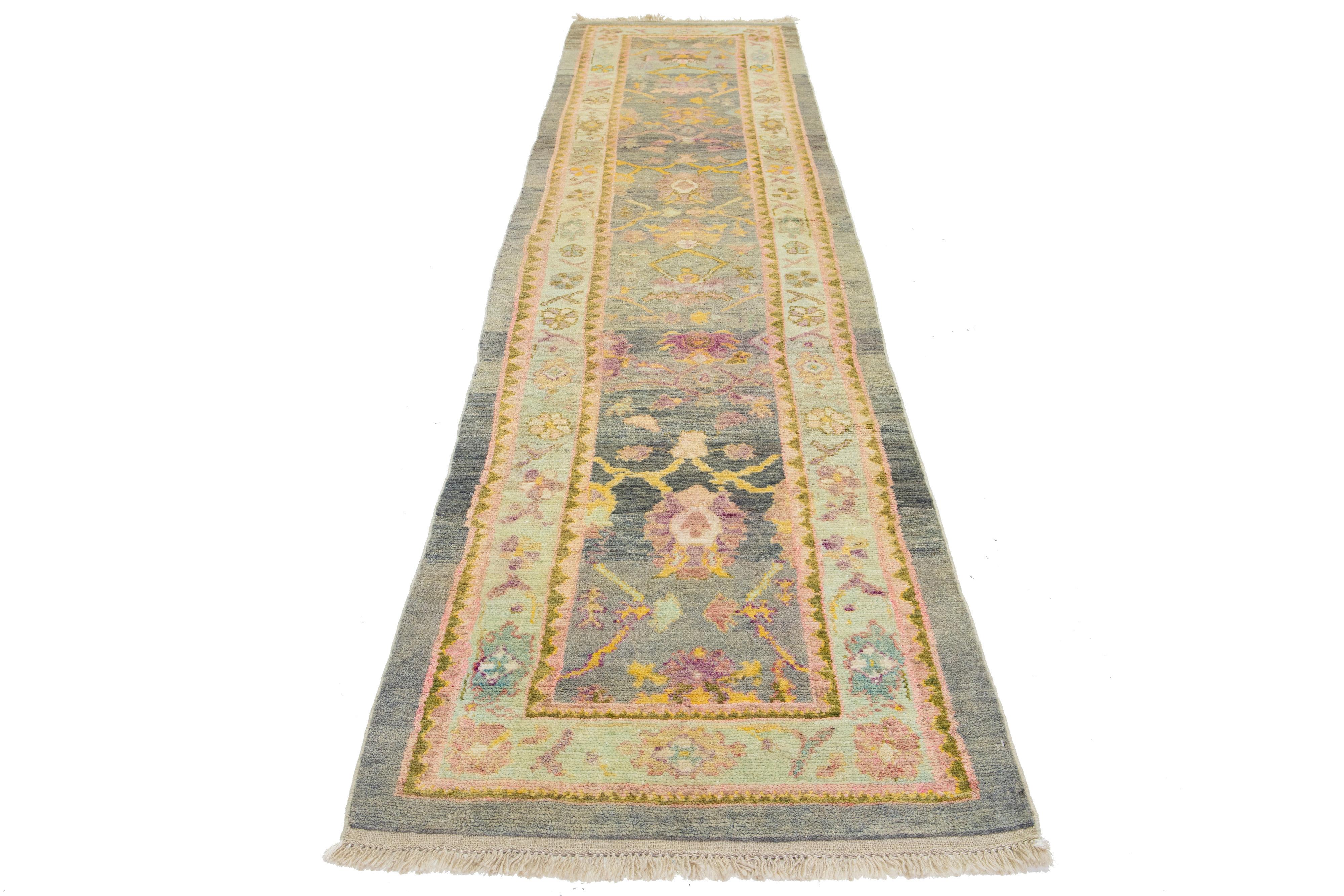 This beautiful modern Oushak hand-knotted wool rug features a gray color field. It is a Turkish piece with stunning accent colors of blue, yellow, pink, and brown, all woven into a gorgeous all-over floral design.

This rug measures 3' x 13'1