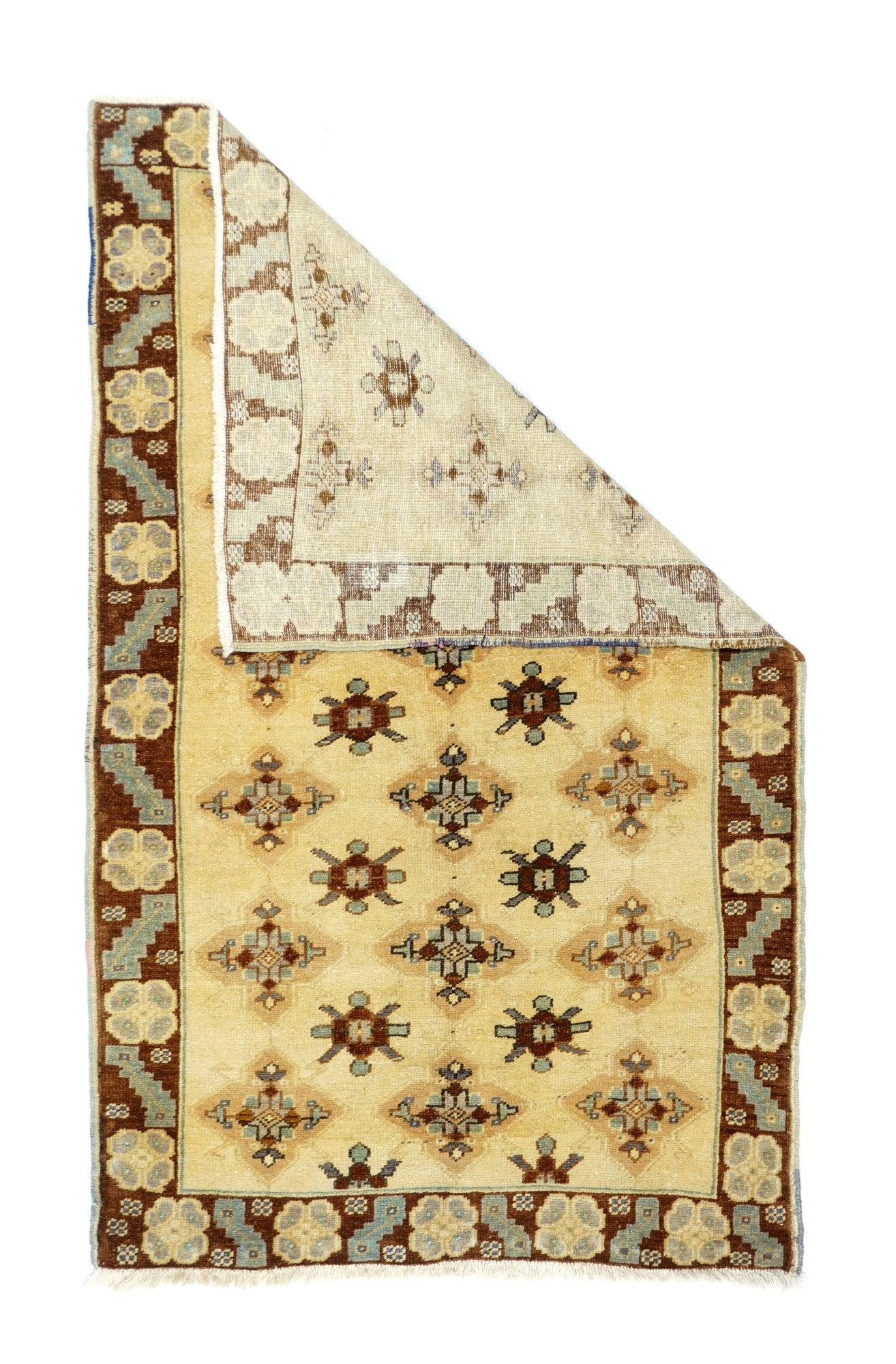 Tapis turc 3'4'' x 5'8''. Le champ de couleur crème sable est orné d'un motif turkmène modifié, composé de guls AINA et de guls Chemche, répartis en cinq colonnes décalées, détaillées en rouge, vert, chamois et ivoire. La bordure de terre de sienne