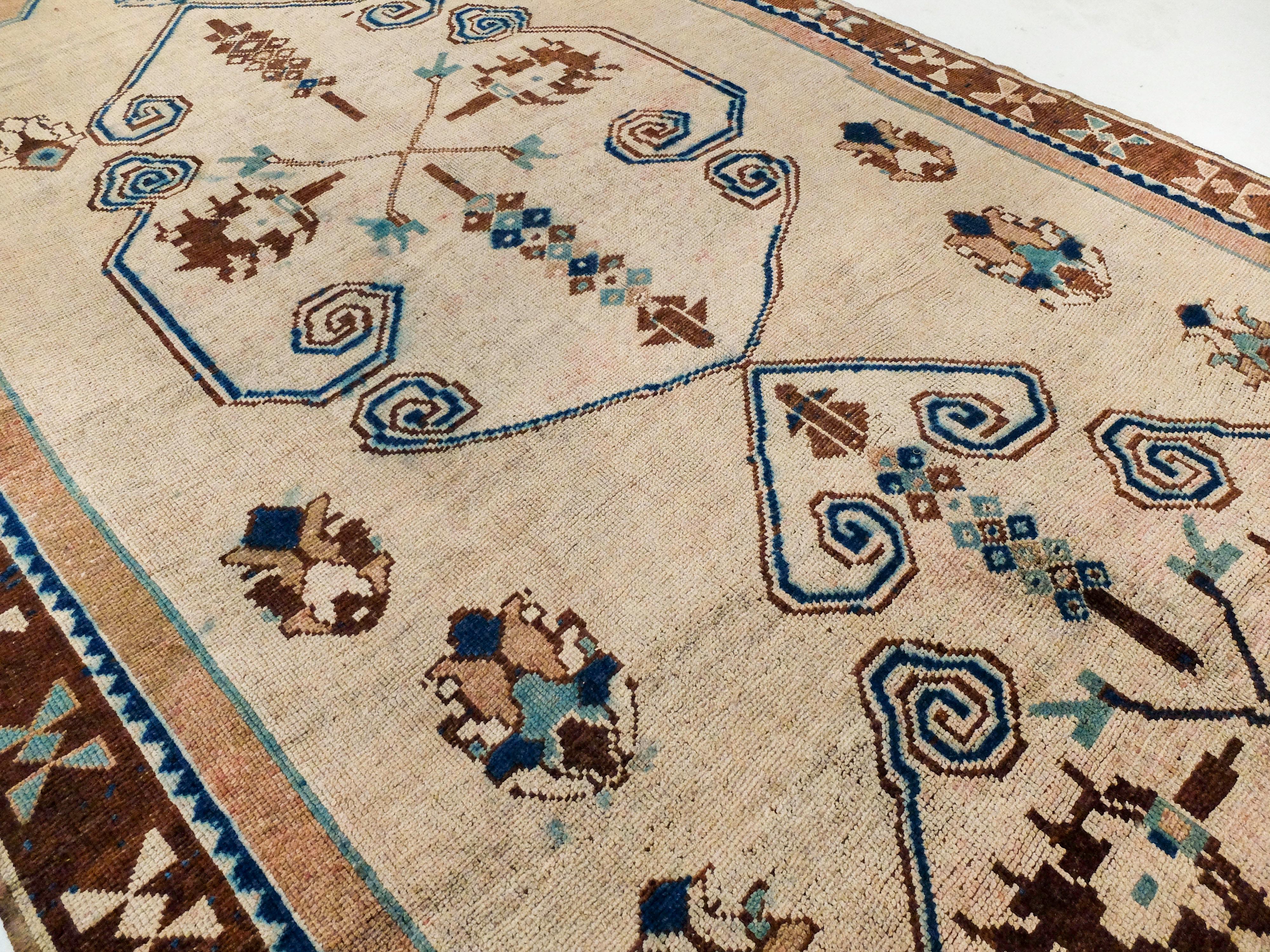 This Turkish antique rug has a distinctive and almost playful pattern. The two main shapes are hand-drawn-like and not perfectly symmetrical adding to the rug's unique quality. Its playful elements include lines with spirals at the end and freely