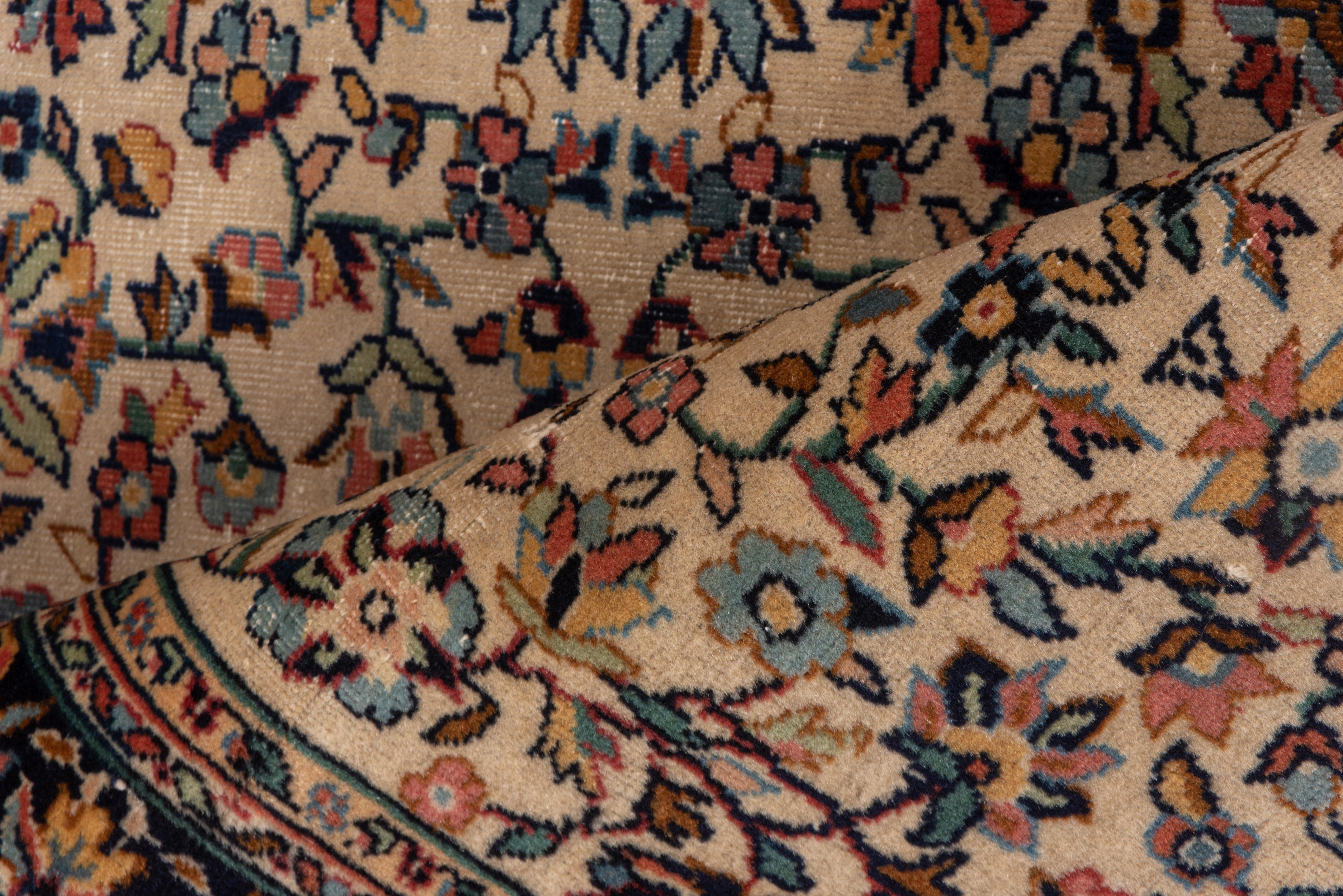 The cream field of this urban East Anatolian small scatter features a vertically slipped all-over pattern of rosettes, vinery, small leaves and florets, detailed in pale blue, tangerine and dark brown. The navy-black main border shows rosettes and