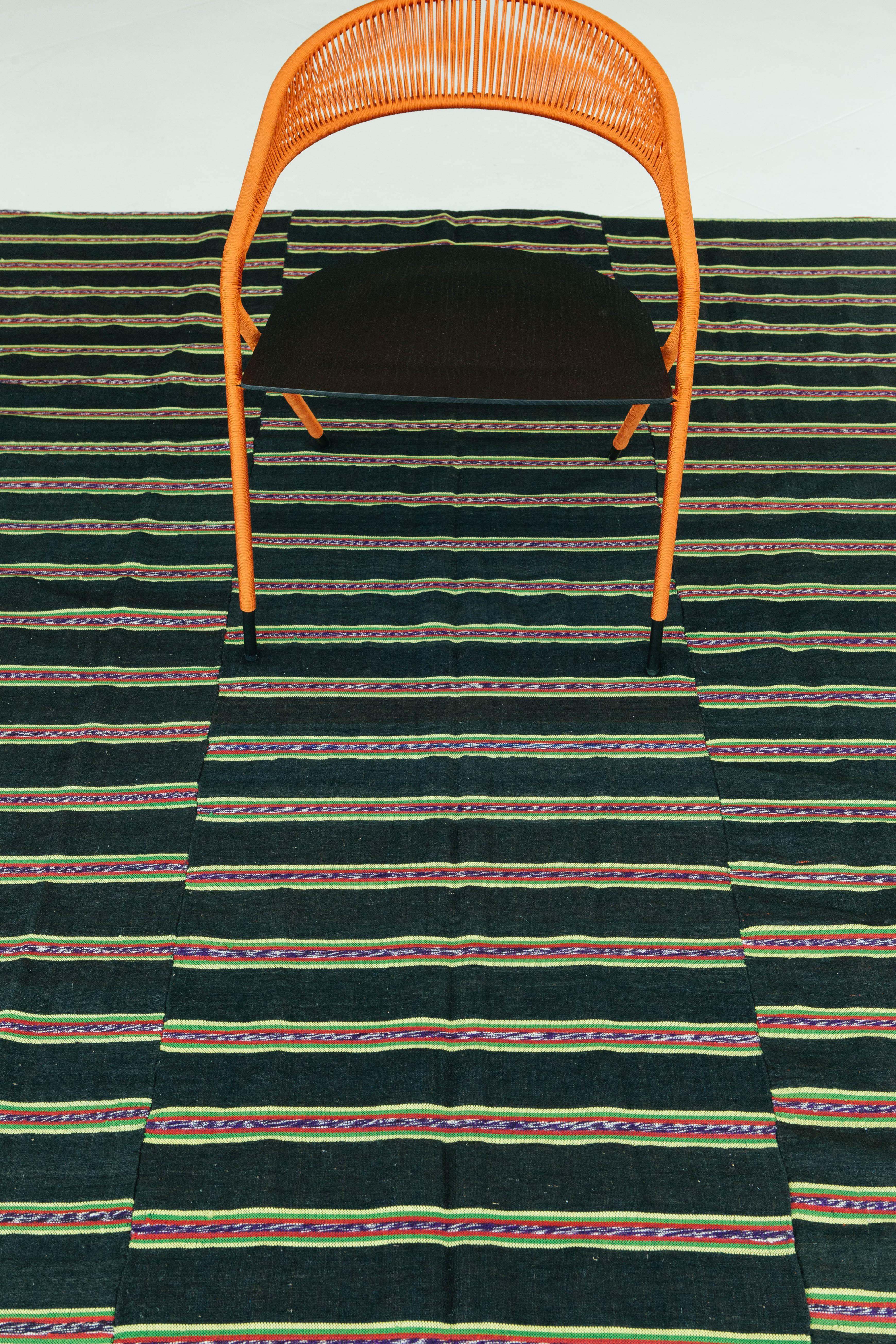 A Turkish Tisse Kilim flat-weave rug with a dark chocolate field and bands of colorful tribal stripes. This Kilim has a triple vertical banding design as well as multicolored tribal horizontal stripes. This rug adds dimension and character to any