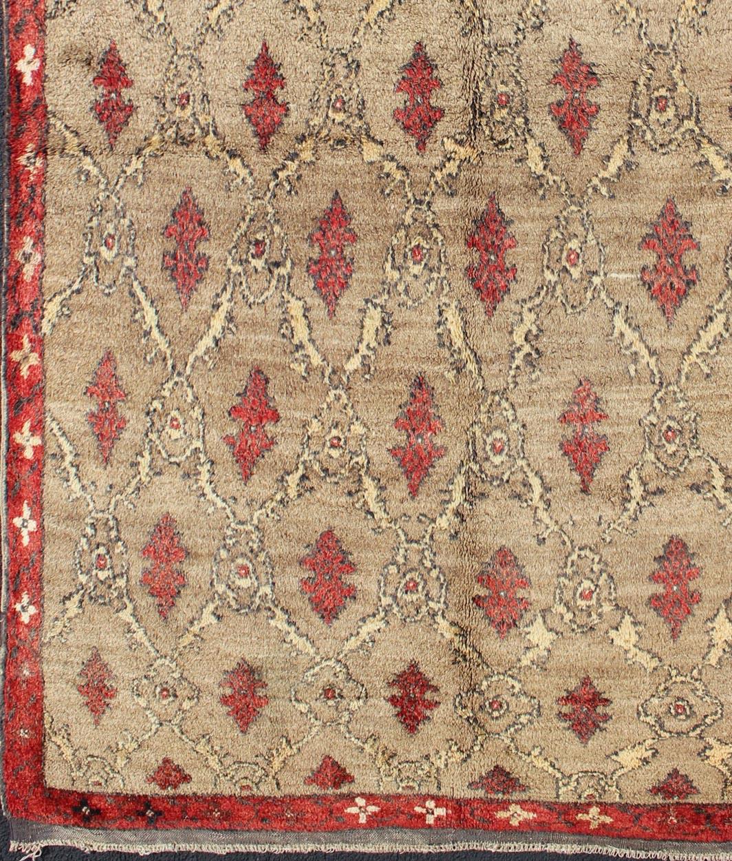 Mid century Tulu carpet in sand color background.

This mid century Tulu rug features repeating red motifs laid across a sand-colored field and enclosed within similarly-colored frames. 

Tulu rugs were woven in Konya area, in central Anatolia,