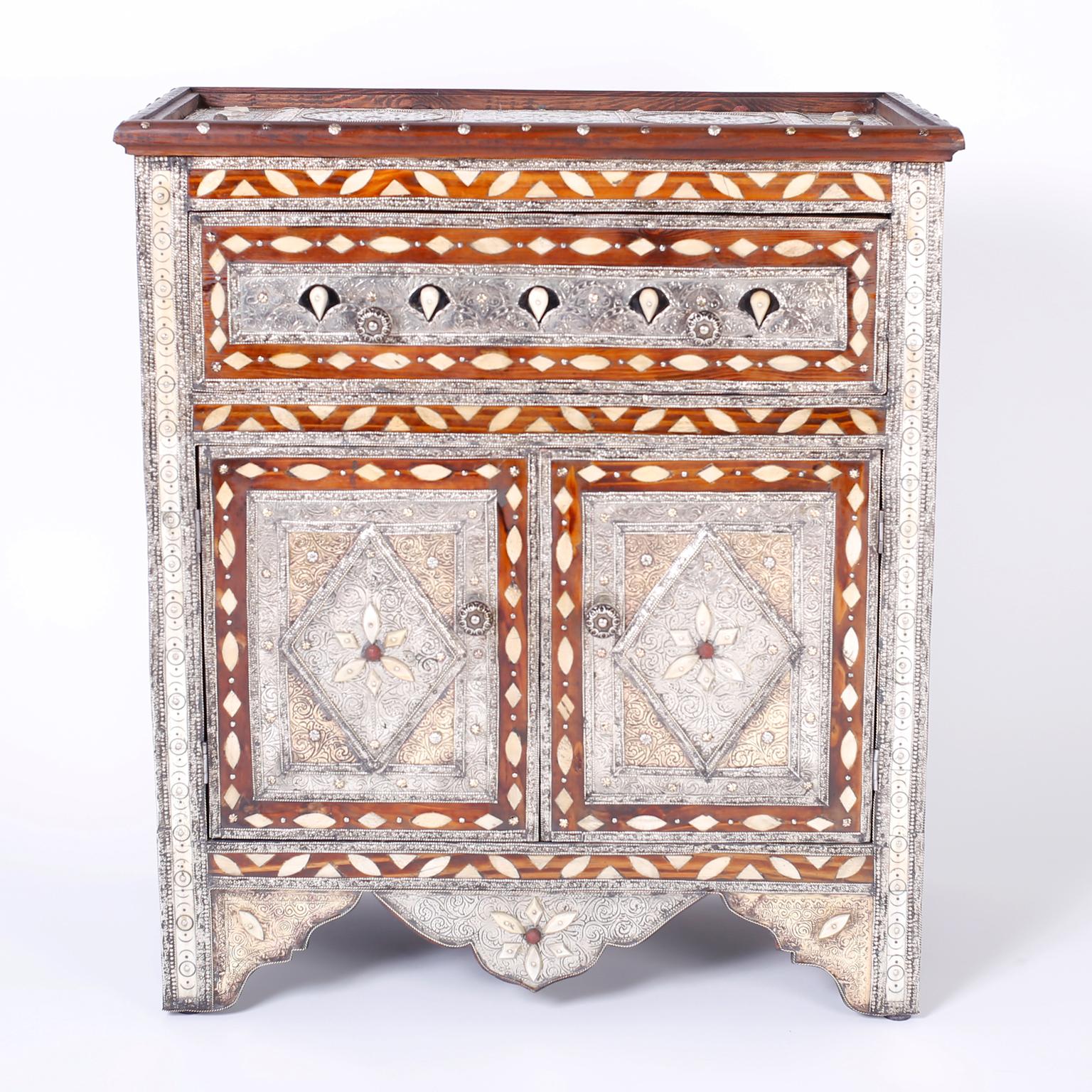 Unique Turkish cabinet or stand showing Syrian influences with elaborate hand hammered floral designs on tin over a hardwood frame. Featuring semi-precious stones, bone inlays, stick and ball panels and plenty of storage with a drawer and two
