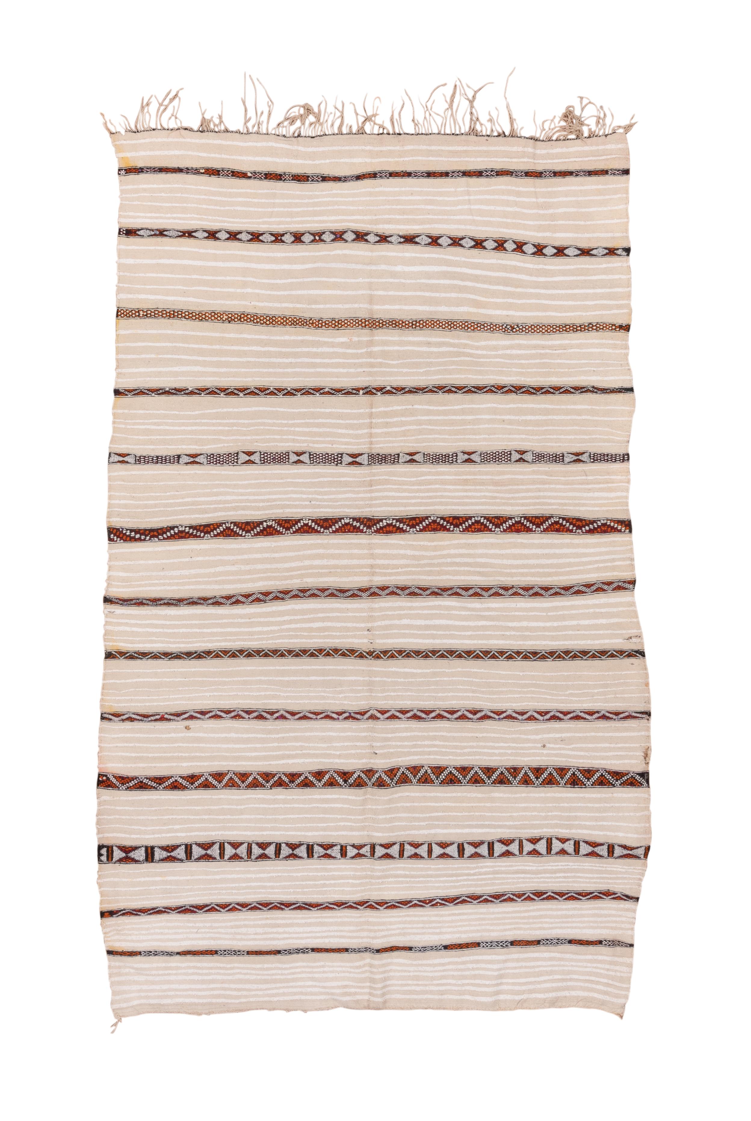 The ecru field is broken up by slender horizontal bands with zig zag and hourglass designs in dark brown. Additional lines run across between the major bands. The handle is soft and floppy, the construction is all wool. Tassels at one end. Good