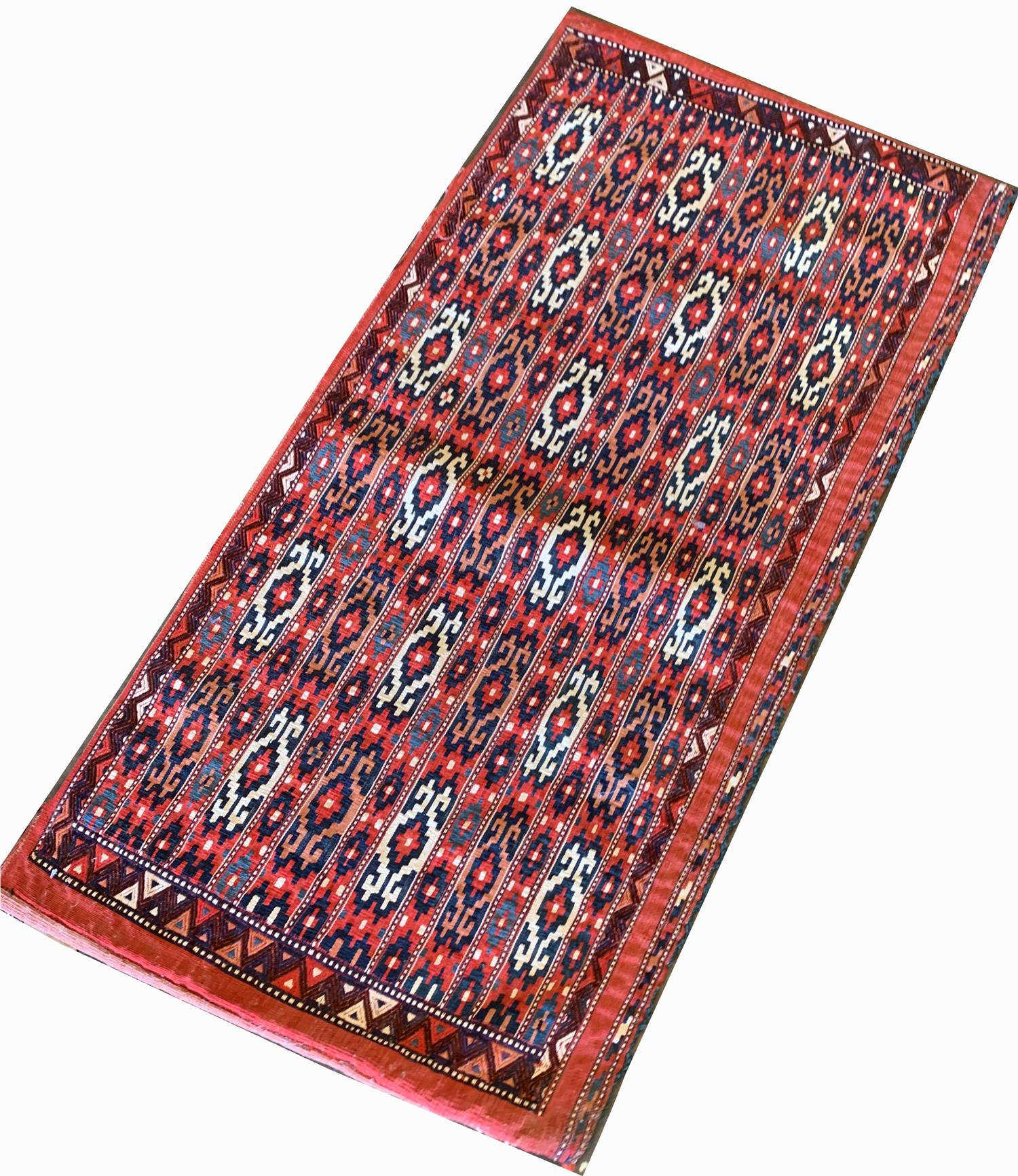 This elegant Turkmen geometric rug is an antique rug handwoven piece constructed in the 1880s with organic materials. The design features a bold red background with blue, orange and white accent colours that make up the geometric design. The design,