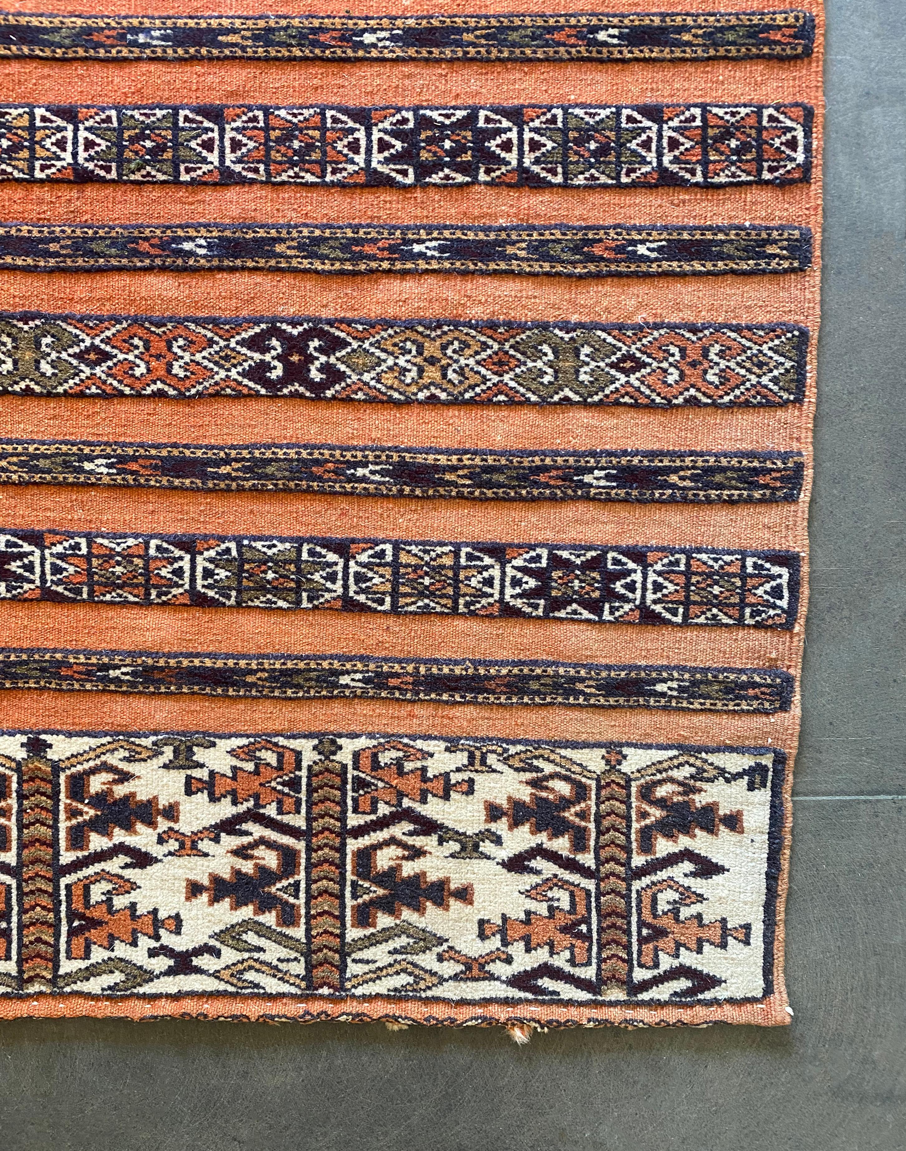 This Yomud tribal rug from Turkmenistan features a striking orange background as well as a mix of tribal detailing and motifs. It is composed of wool and originates from the early 20th century. 

Dimensions: Length 94cm x Width 130cm.