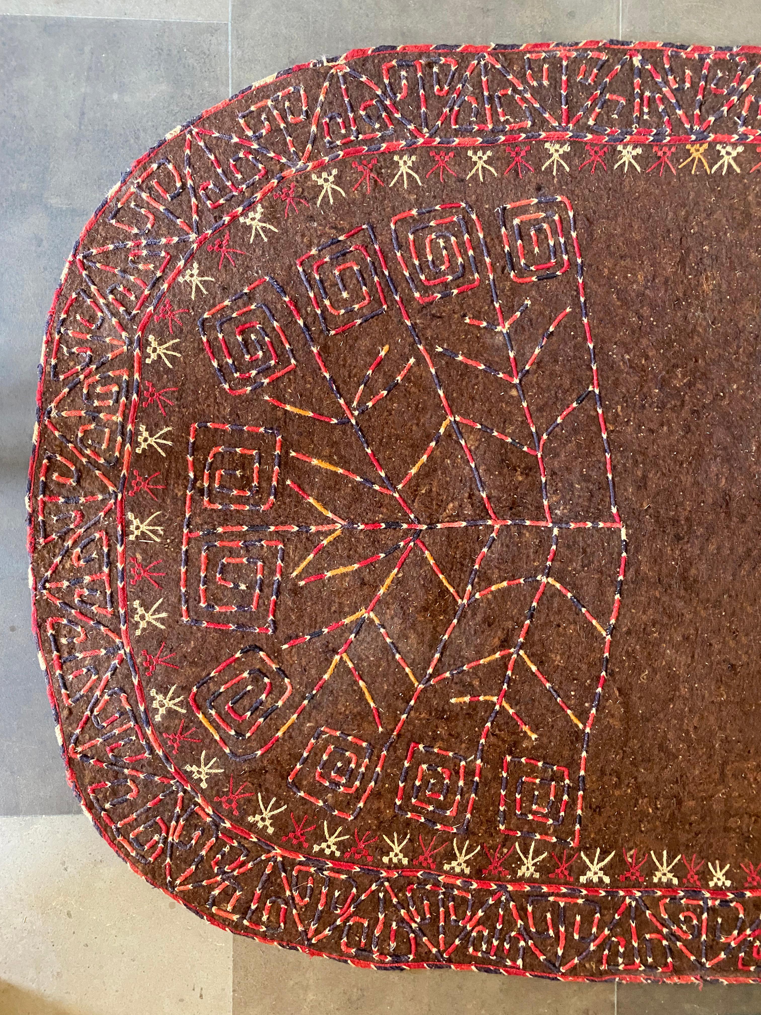 This Turkmenistan Yomud tribe ceremonial horse blanket is crafted from brown felt wool and dates to the early 20th Century. It features a mix embroidered tribal patterns and motifs as well as side flaps. This blanket would have been used exclusively