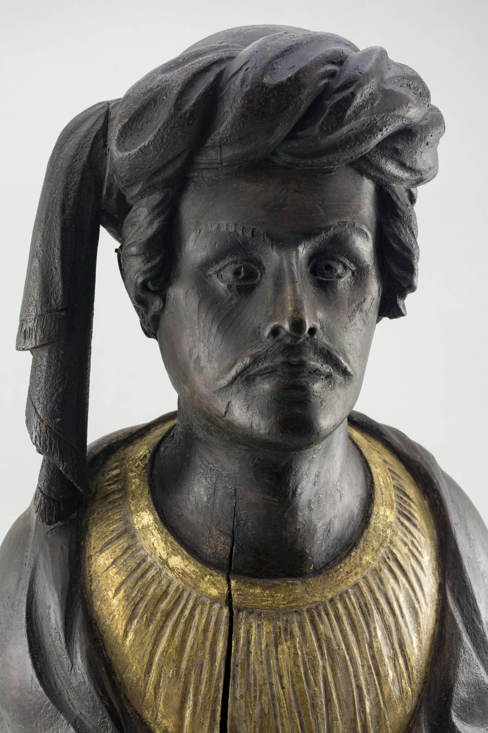 Carved figural bust out of a block of Pine. The 
man’s face with a mustache wearing a turban
with remnants of paint, American, circa 1840
Measures: 25” high.

 