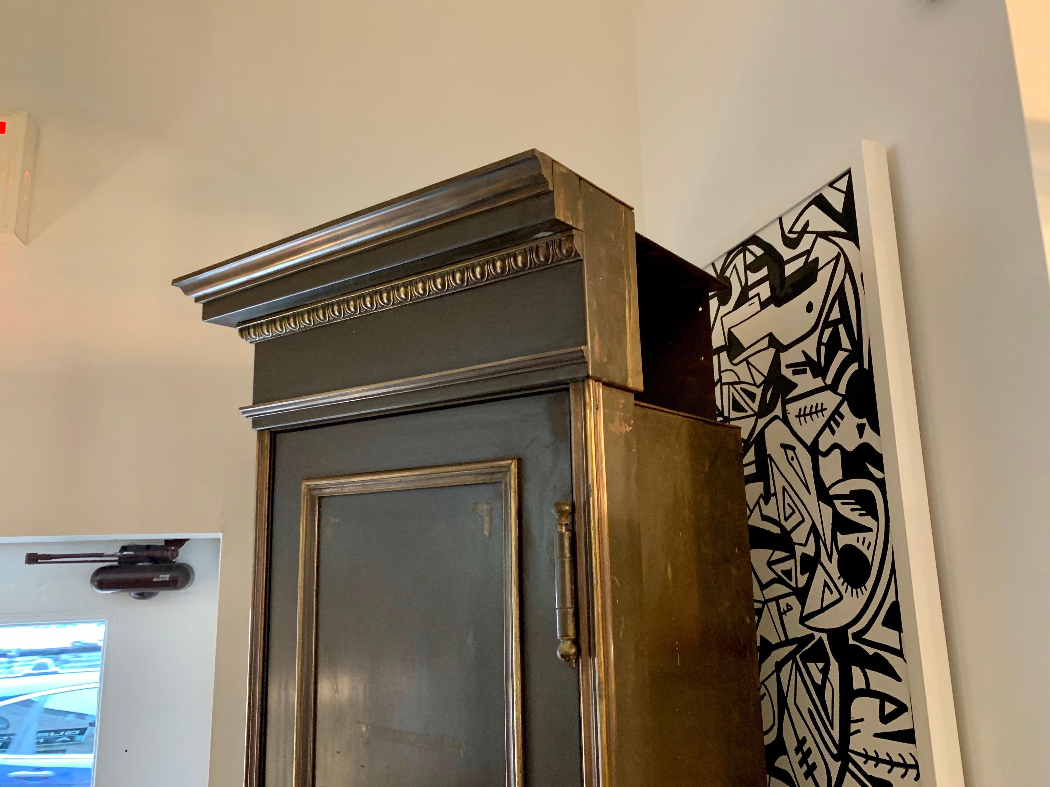 This very heavy iron and bronze detailed tall locker with black Belgian marble base is all original. Interior details include a heavy turning handle door which opens to hooks and shelves for storage. Never restored, original bronze tone - was part