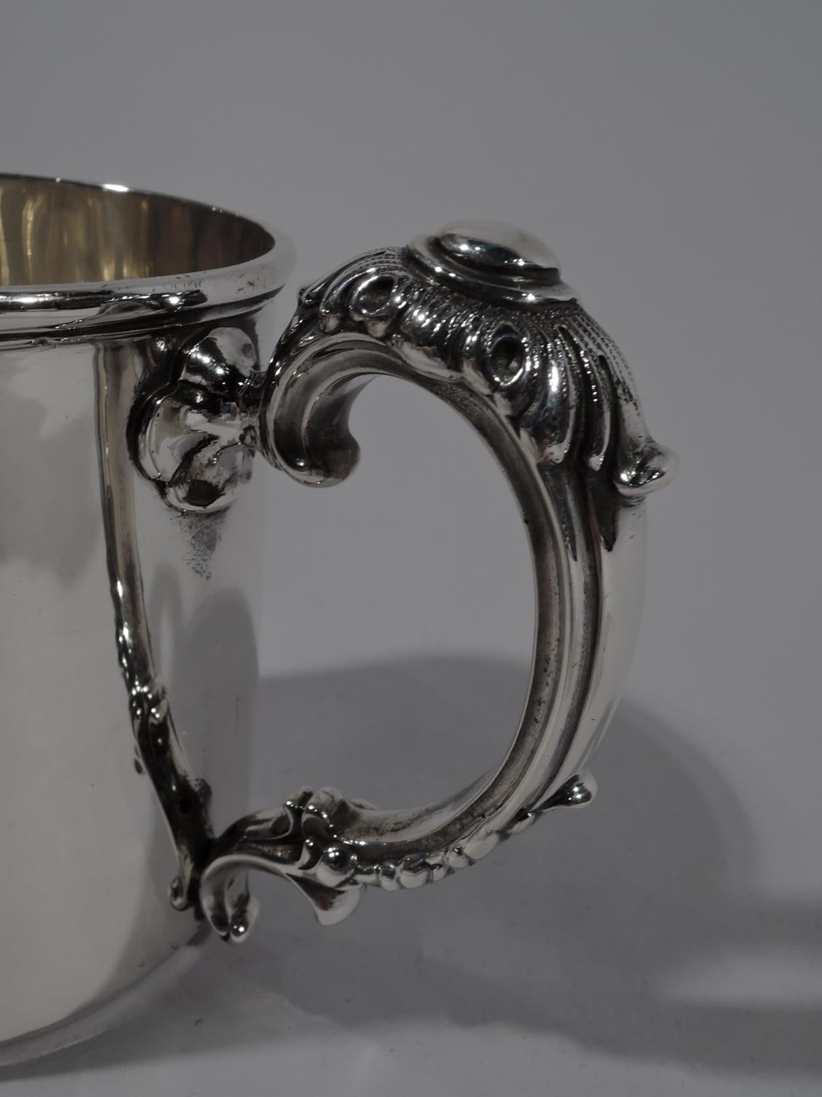 Turn-of-the-century American sterling silver baby cup. Straight sides and short inset foot. Rim molded with pendant fleurs-de-lys. Restrained ornament and lots of room for engraving with the fancy bits confined to the high-looping, double-scroll,