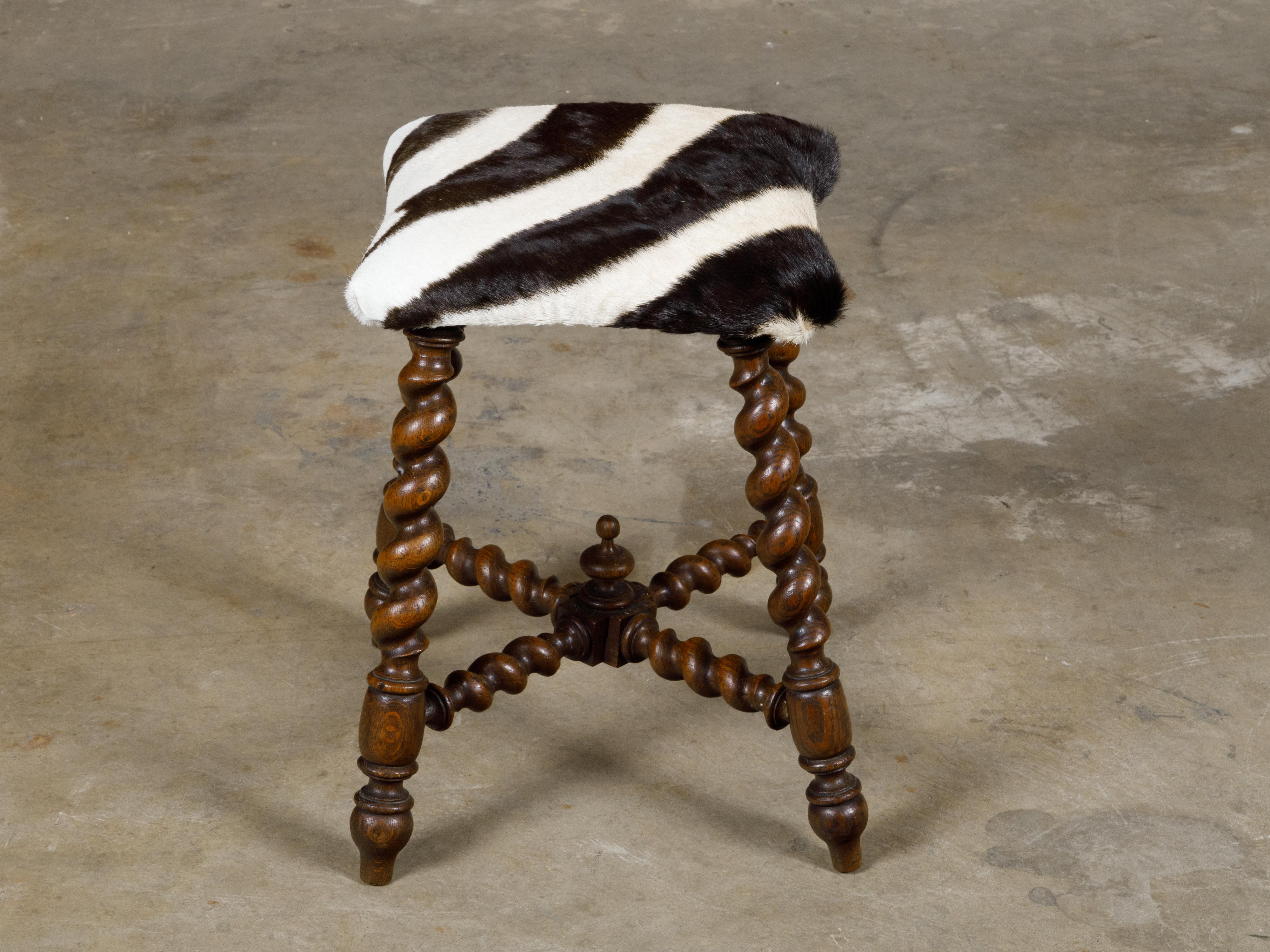 An English Turn of the Century barley twist stool from circa 1900 with zebra hide upholstery and X-Form cross stretcher. Immerse yourself in the unique blend of traditional English craftsmanship and exotic flair with this Turn of the Century barley