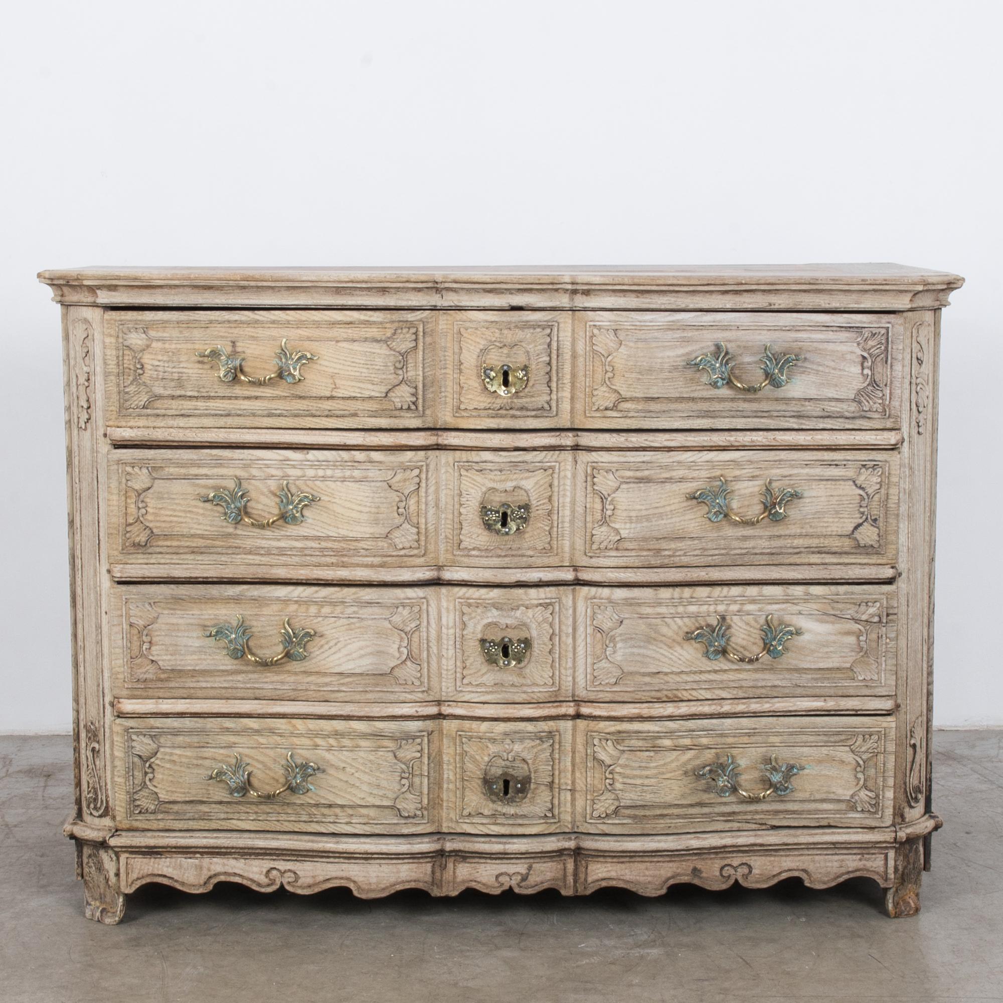 A chest of drawers from Belgium, circa 1900. With a romantic rococo influence, four drawers feature a gentle serpentine curve. Each drawer features cast bronze handles, in a leafy organic form. Leafy frames and sculpted metal give a romantic effect.