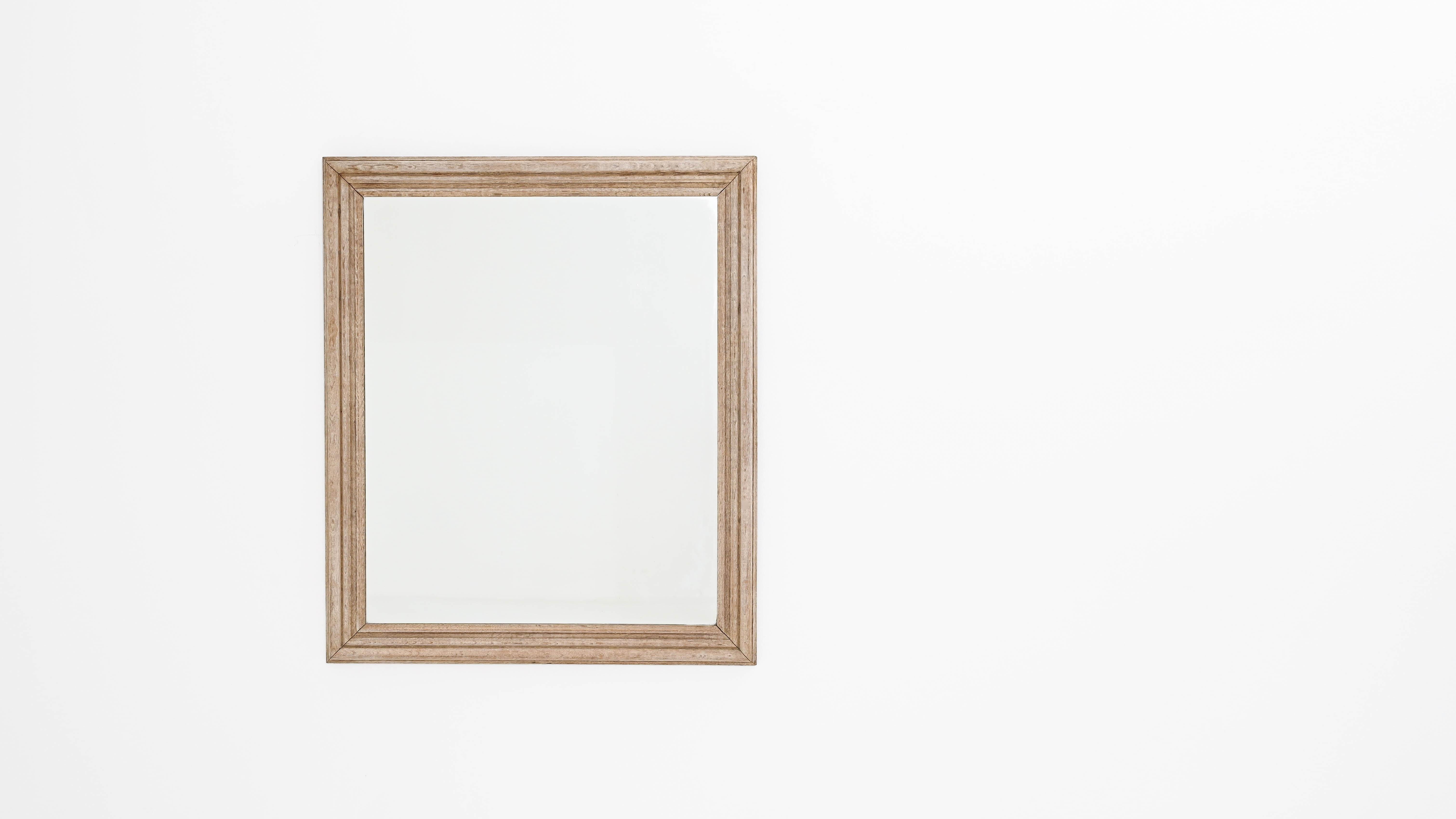 This vintage mirror in natural oak has an elegant simplicity. Made in Belgium at the turn of the century, the clean lines of the wooden frame border an ample pane of bright glass. The large size of the mirror naturally amplifies the light in a room,