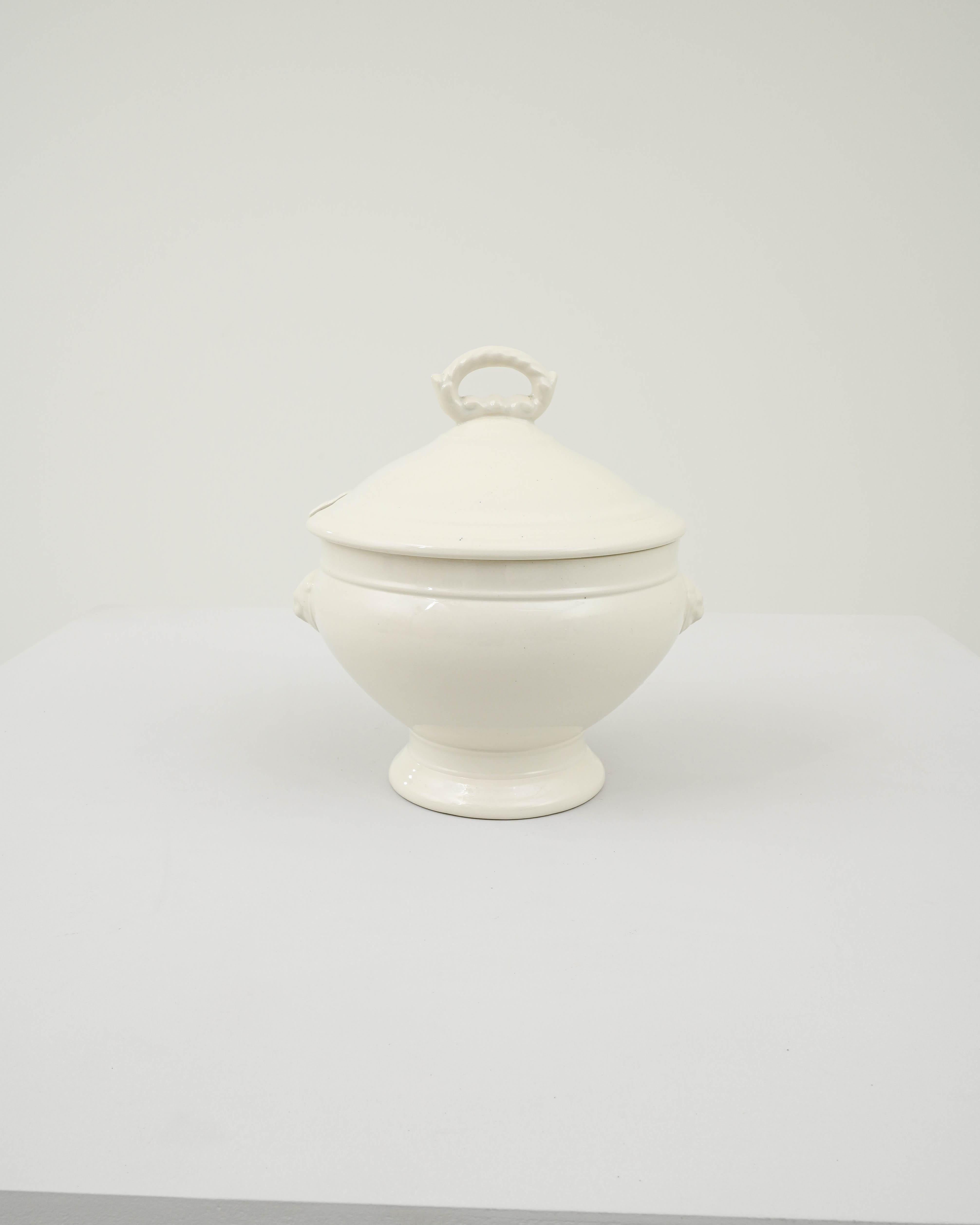 This elegant vintage porcelain tureen offers an attractive centerpiece. Made in Belgium at the turn of the century, the soft curves of the form are emphasized by the silken finish and pristine white of the ceramic. A lion head in raised relief