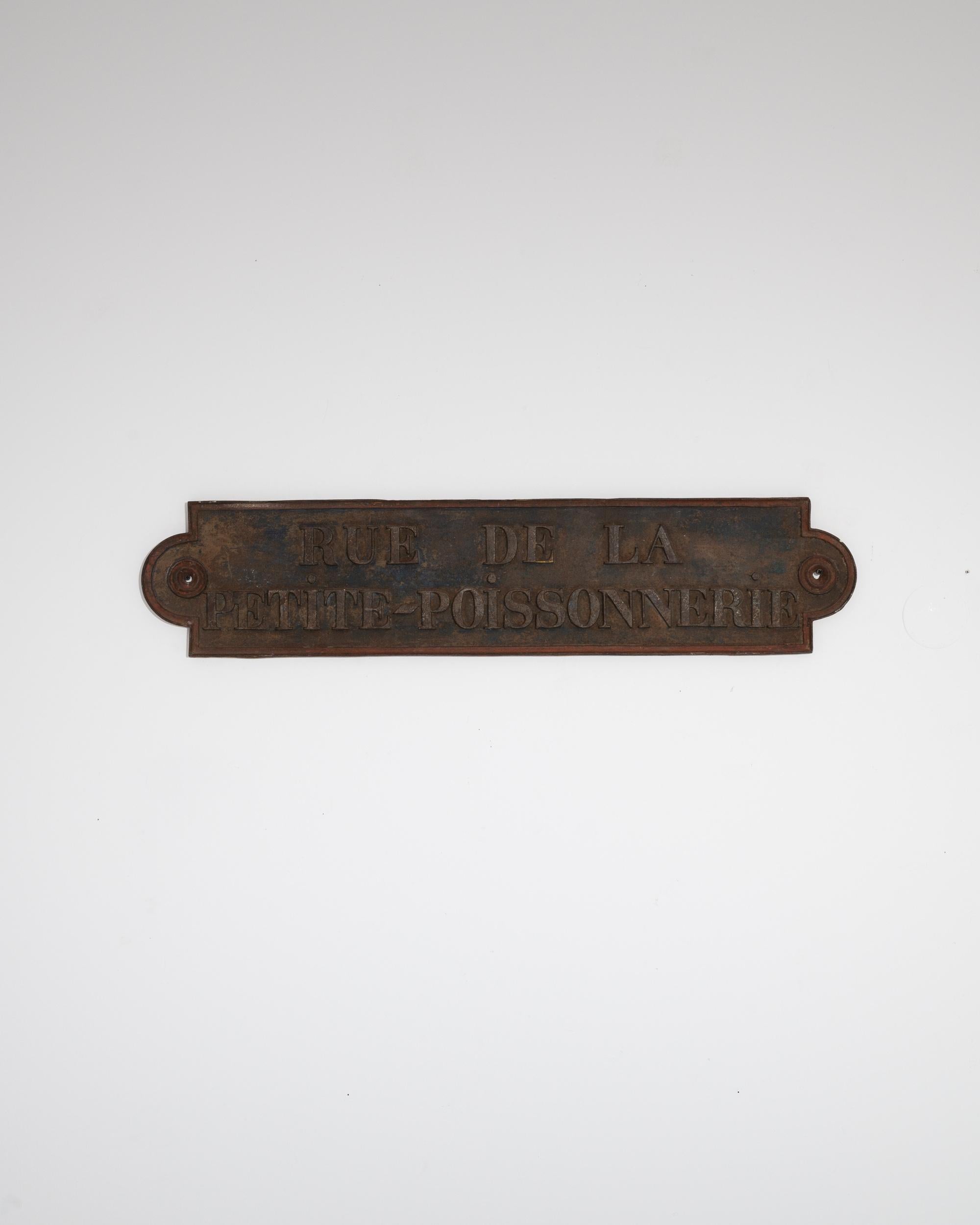 A unique and poignant vintage piece, this cast iron street sign offers a glimpse of bygone Paris. Used around the turn of the century, the street which the sign designates —rue de la petite poissonnerie, or street of the small fish market —no longer
