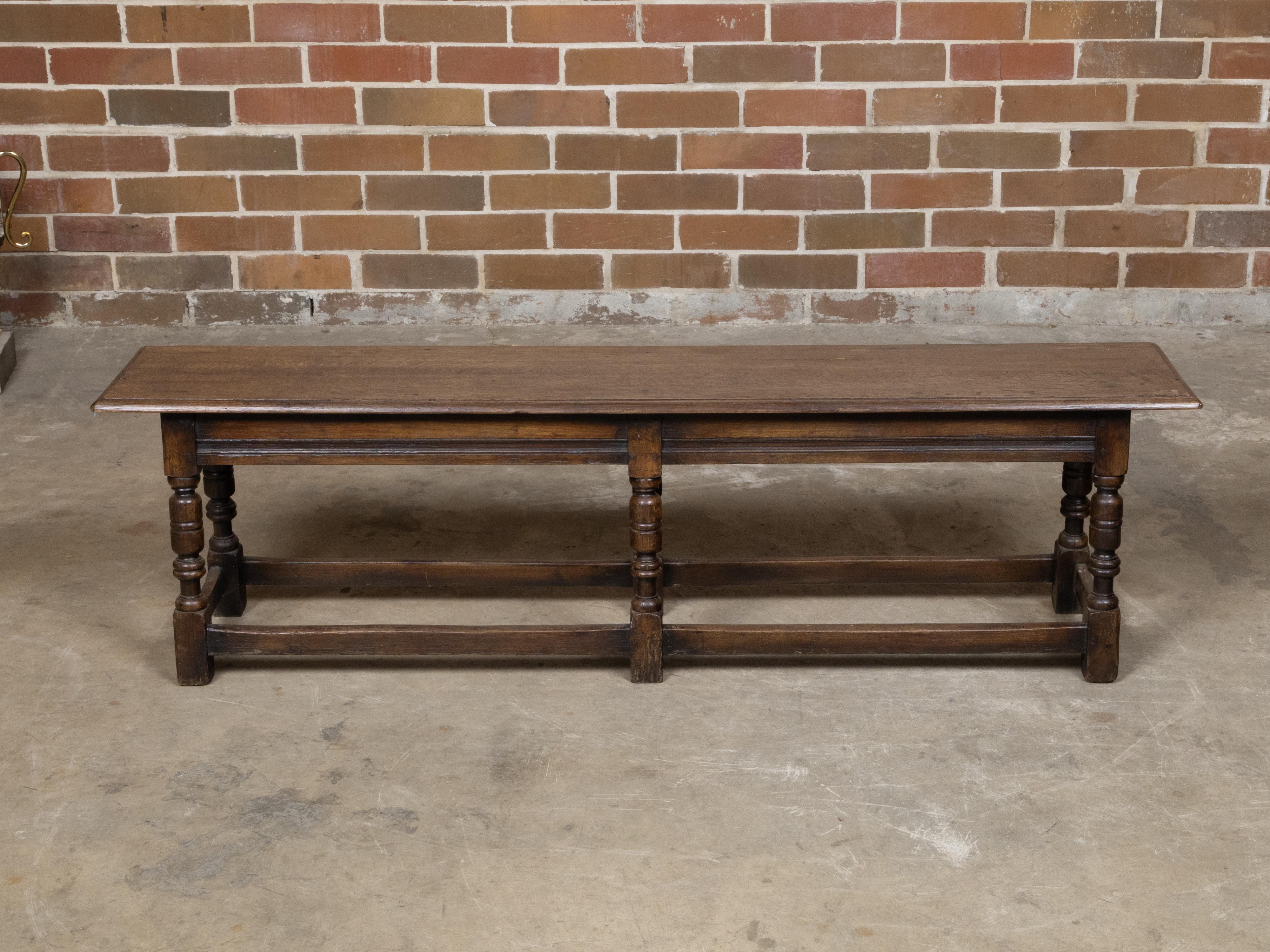 Panca inglese di fine secolo in quercia del 1900 circa con gambe a balaustro tornite e barelle laterali. Questa panca inglese di fine secolo in rovere, risalente al 1900 circa, cattura la nostra attenzione per il suo affascinante carattere rustico e