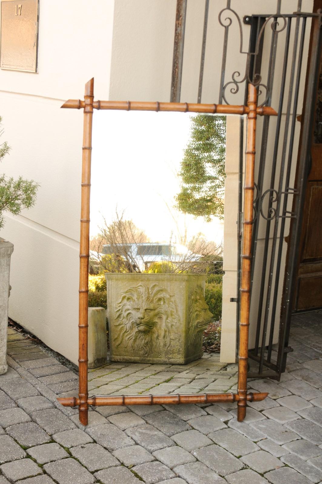 A French rustic faux-bamboo mirror from the early 20th century, with honey brown patina. Born in France at the turn of the century, this charming mirror features a linear silhouette made of a honey brown hued faux bamboo frame, with intersecting