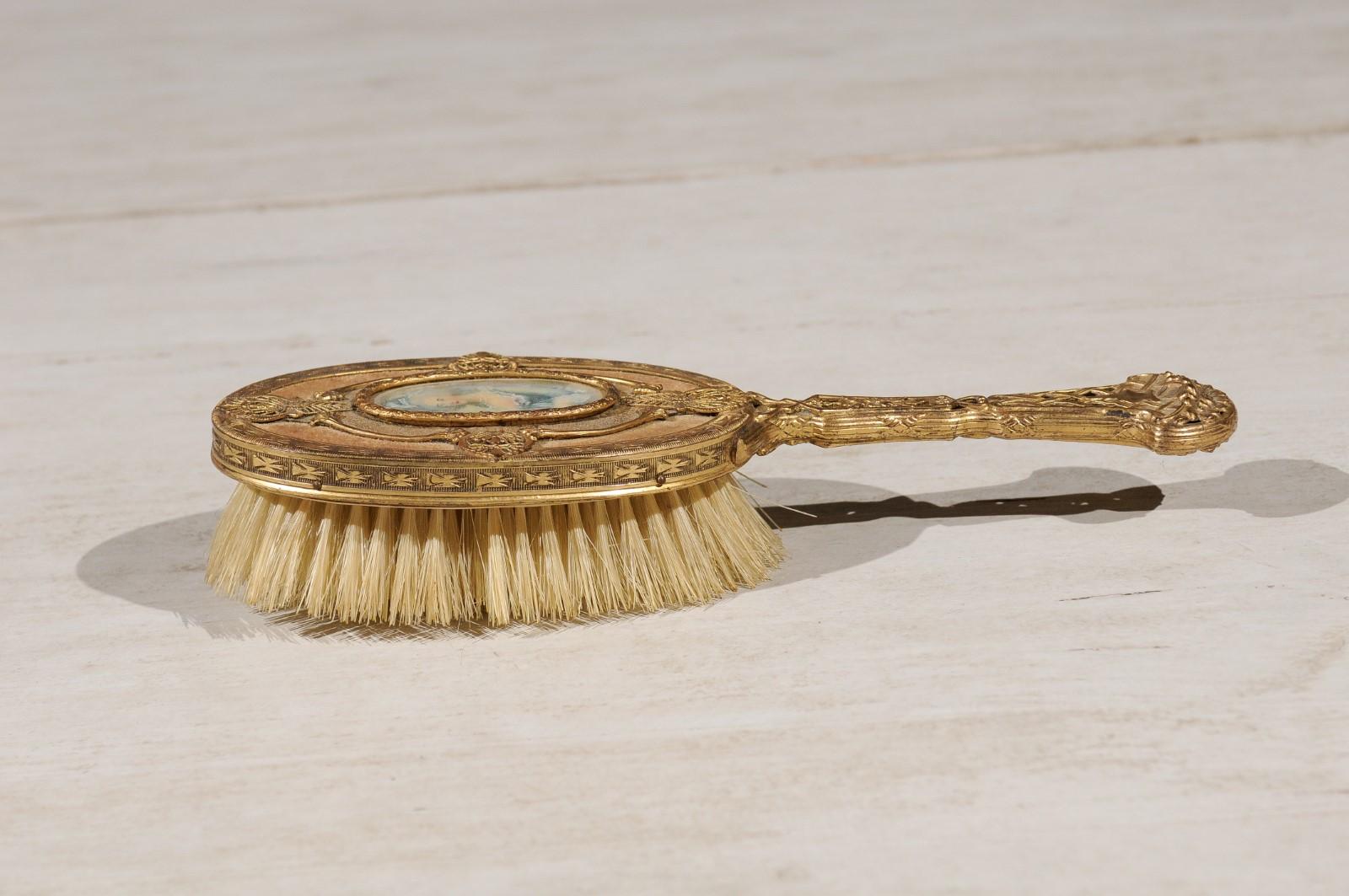 A French brass filigree horsehair brush from the Turn of the century, with hand painted portrait. Born in France at the end of the 19th, early 20th century, this lovely brush features a brass body presenting a filigree décor. A medallion, depicting