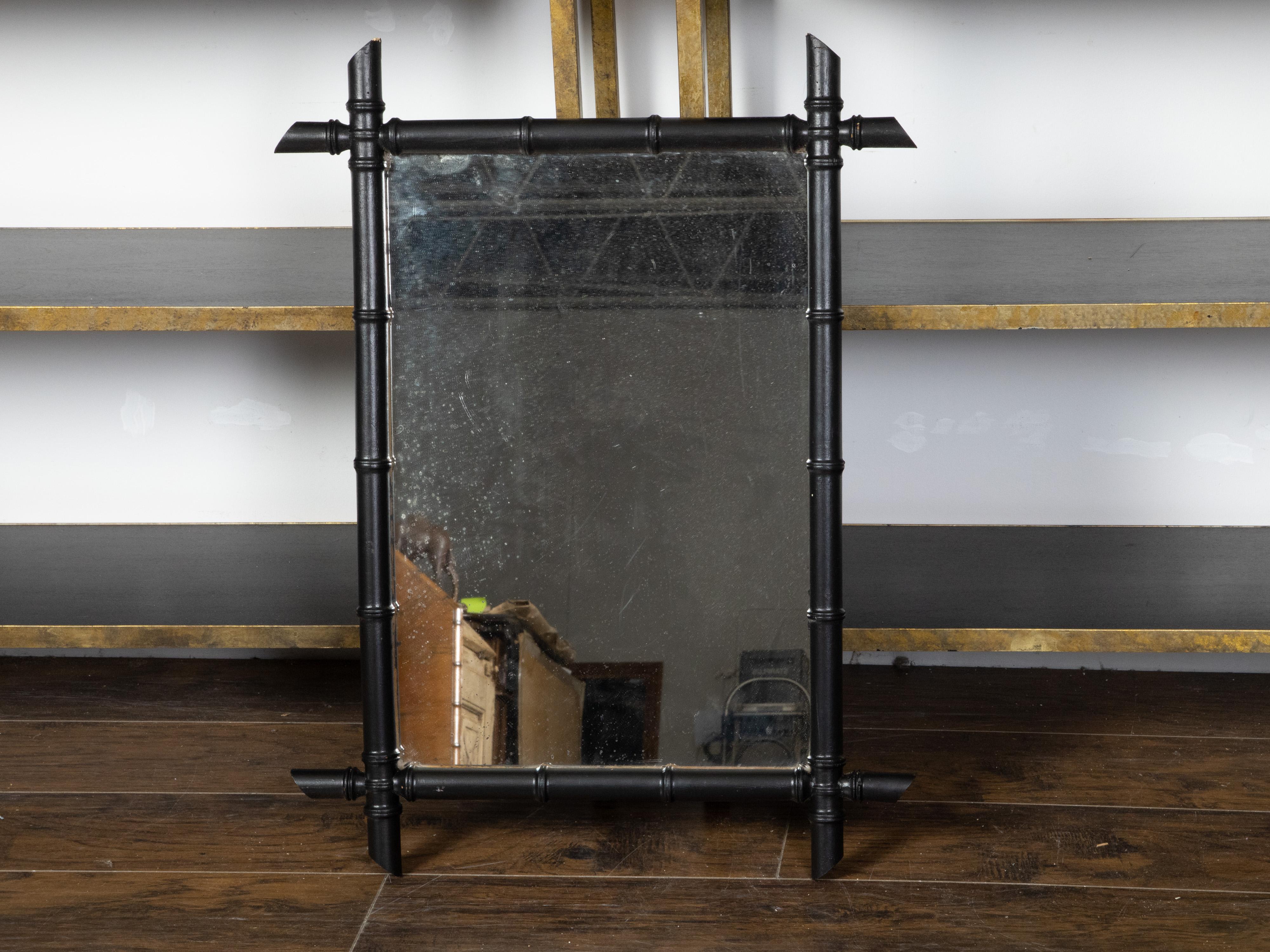 A French faux-bamboo rectangular mirror from the early 20th century, with ebonized finish. Created in France during the Turn of the Century, this mirror features a rectangular silhouette made of an ebonized faux bamboo frame presenting intersecting